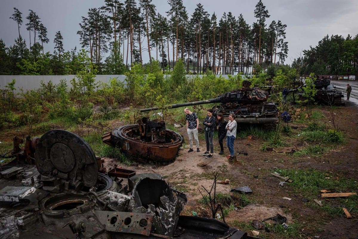 Des Ukrainiens observent la carcasse d'un char russe près de Kyïv, le 30 mai 2022.