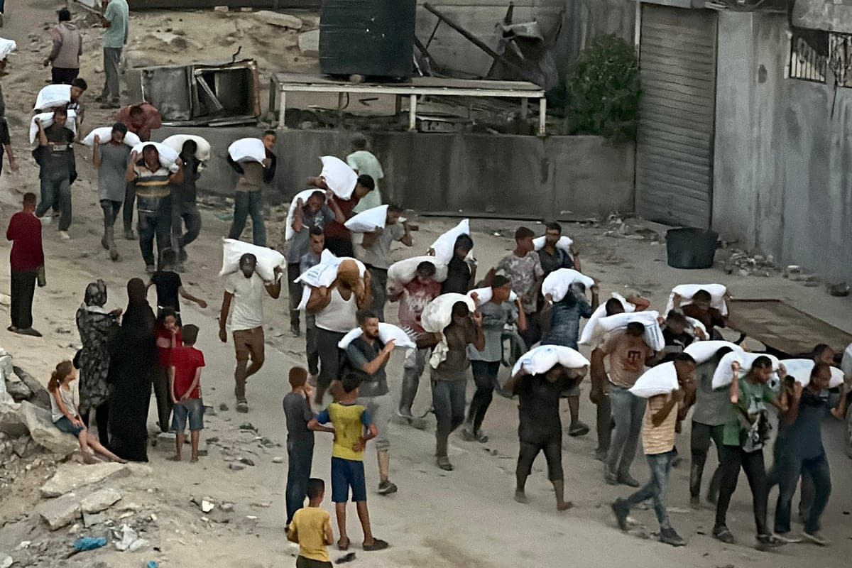 Des hommes transportant des sacs de farine dérobés dans un camion transportant de la nourriture.