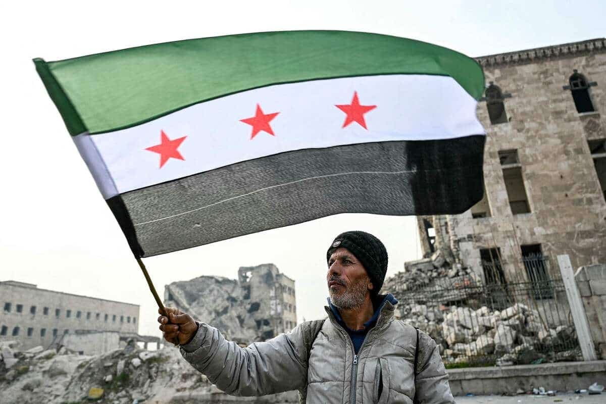 Un homme porte un drapeau syrien à Alep