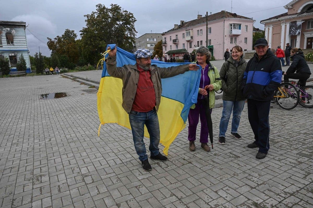 Un homme brandit un drapeau ukrainien à Izioum, dans la région de Kharkiv, dans l'est de l'Ukraine, le 14 septembre 2022. (Photo de Juan BARRETO / AFP)