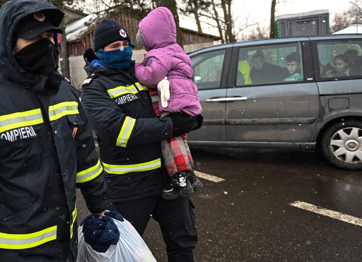 Un pompier roumain tient dans ses bras une jeune réfugiée ukrainienne.