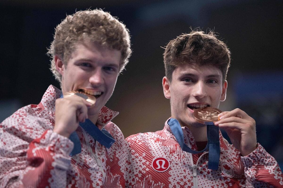 Rylan Wiens et Nathan Zsombor-Murray (à droite) croquent dans leur médaille de bronze obtenue au 10 m synchronisé, lundi aux Jeux olympiques, à Paris.