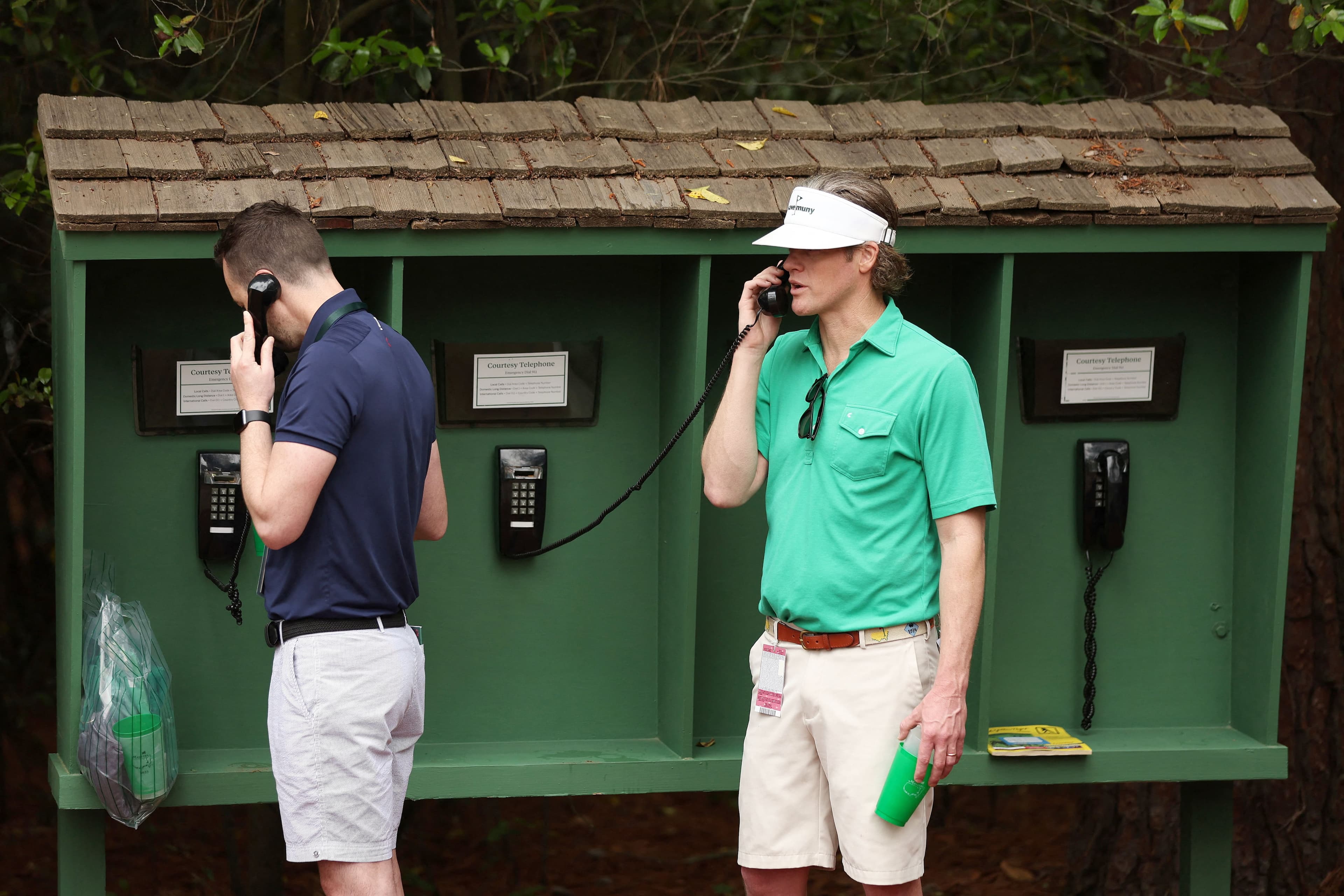 Des spectateurs passent un coup de fil d'un téléphone avec ligne terrestre au Augusta National lors du Tournoi des Maîtres.