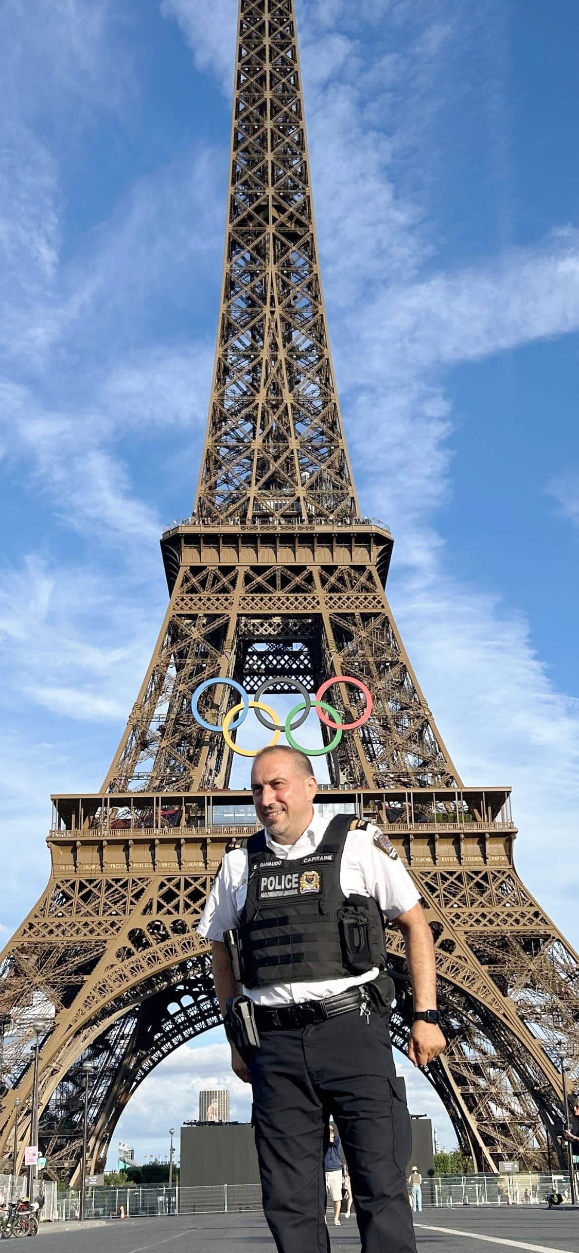 Eddy Ranaudo, capitaine de la section du soutien aux enquêtes au Service de police de l’agglomération de Longueuil, devant la tour Eiffel, décorée des anneaux olympiques.