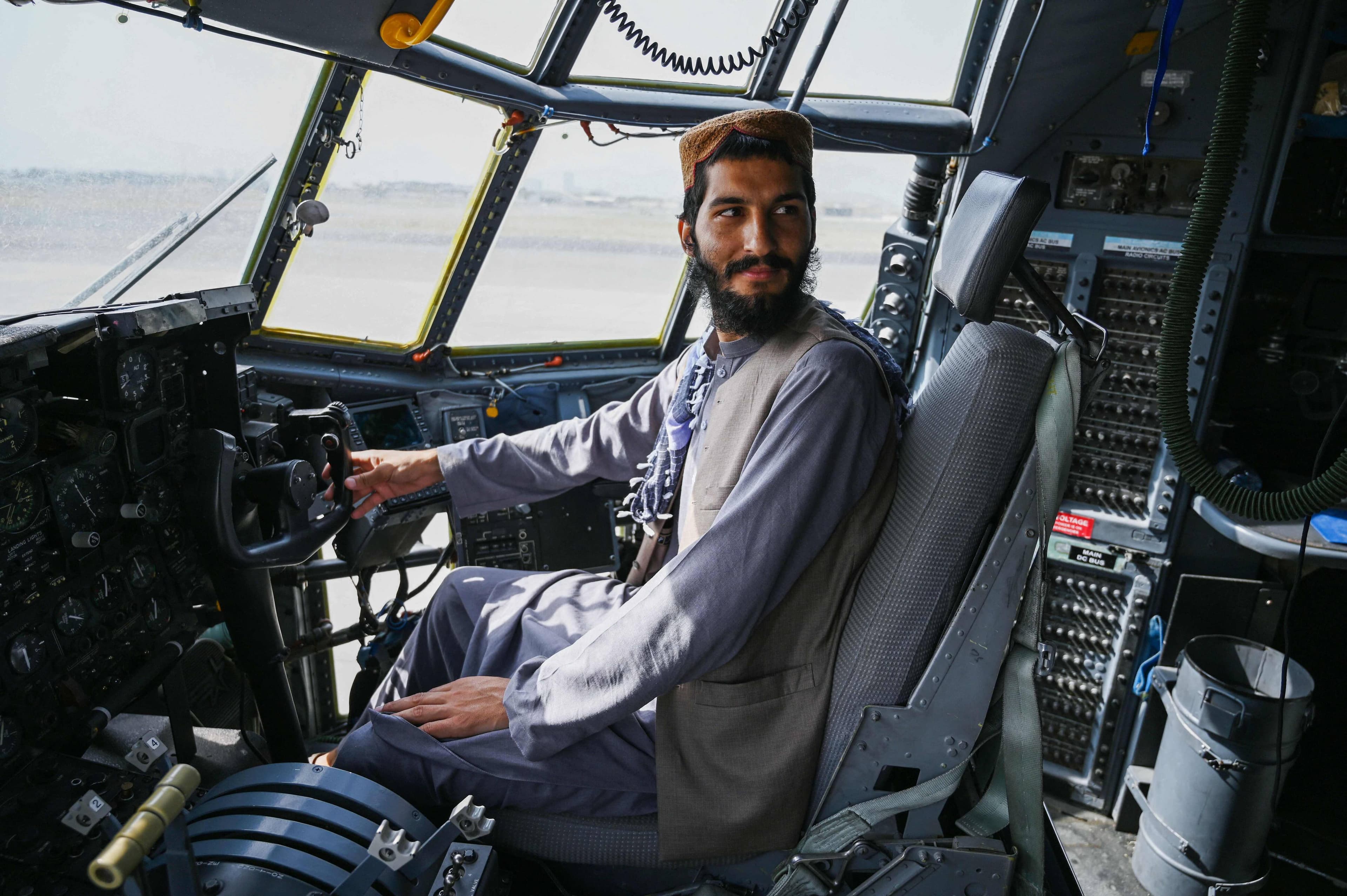 Un Taliban s'assoit aux commandes d'un appareil abandonné de l'armée afghane, à Kaboul.