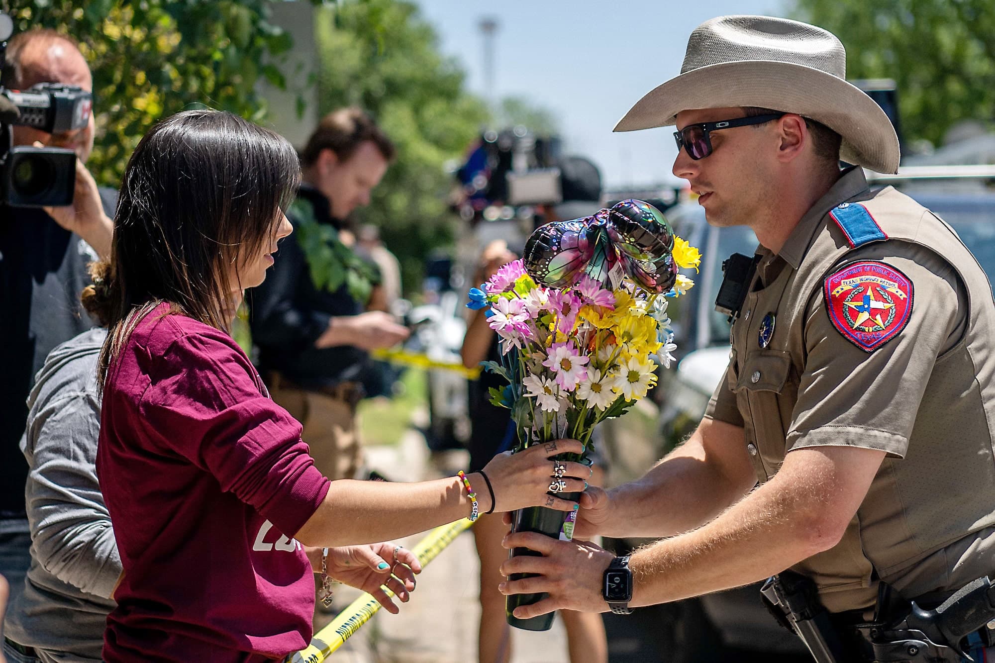 Manda Welch donne un bouquet de fleurs à un policier pour qu’il le dépose devant l’école, où l’enquête se poursuit.