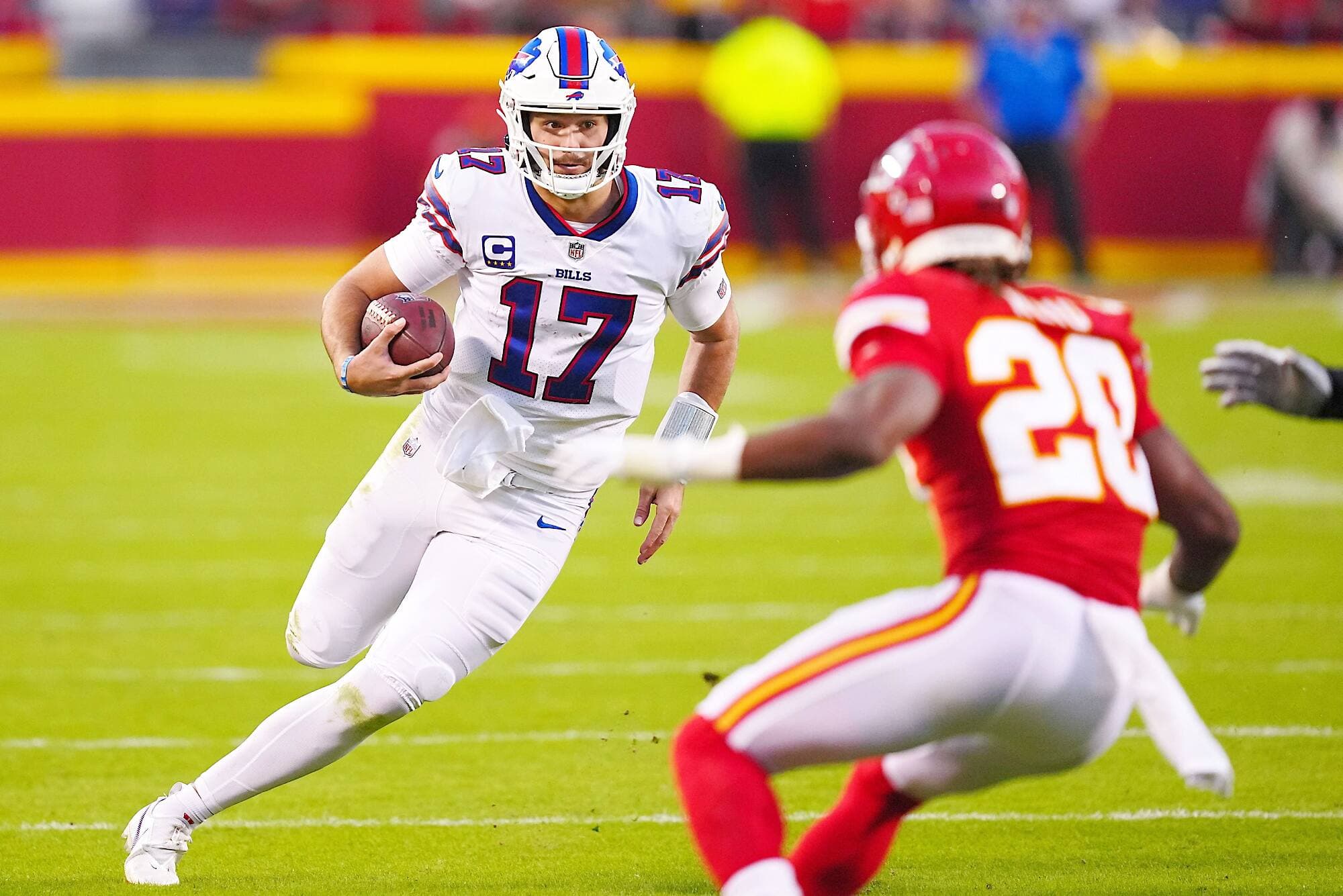 Josh Allen court avec le ballon devant Justin Reid, tout juste avant de sauter par-dessus le joueur des Chiefs.