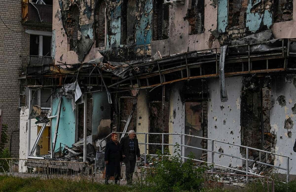 Un couple marche devant un immeuble détruit de Izioum.
