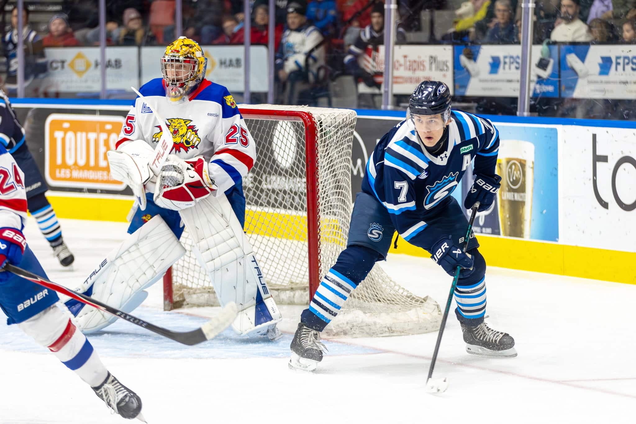 L'attaquant des Saguenéens Maxim Massé représente une menace autour du filet défendu par le gardien des Wildcats de Moncton Rudy Guimond, le 24 janvier 2026, durant un match de saison régulière de la LHJMQ disputé à Chicoutimi.
