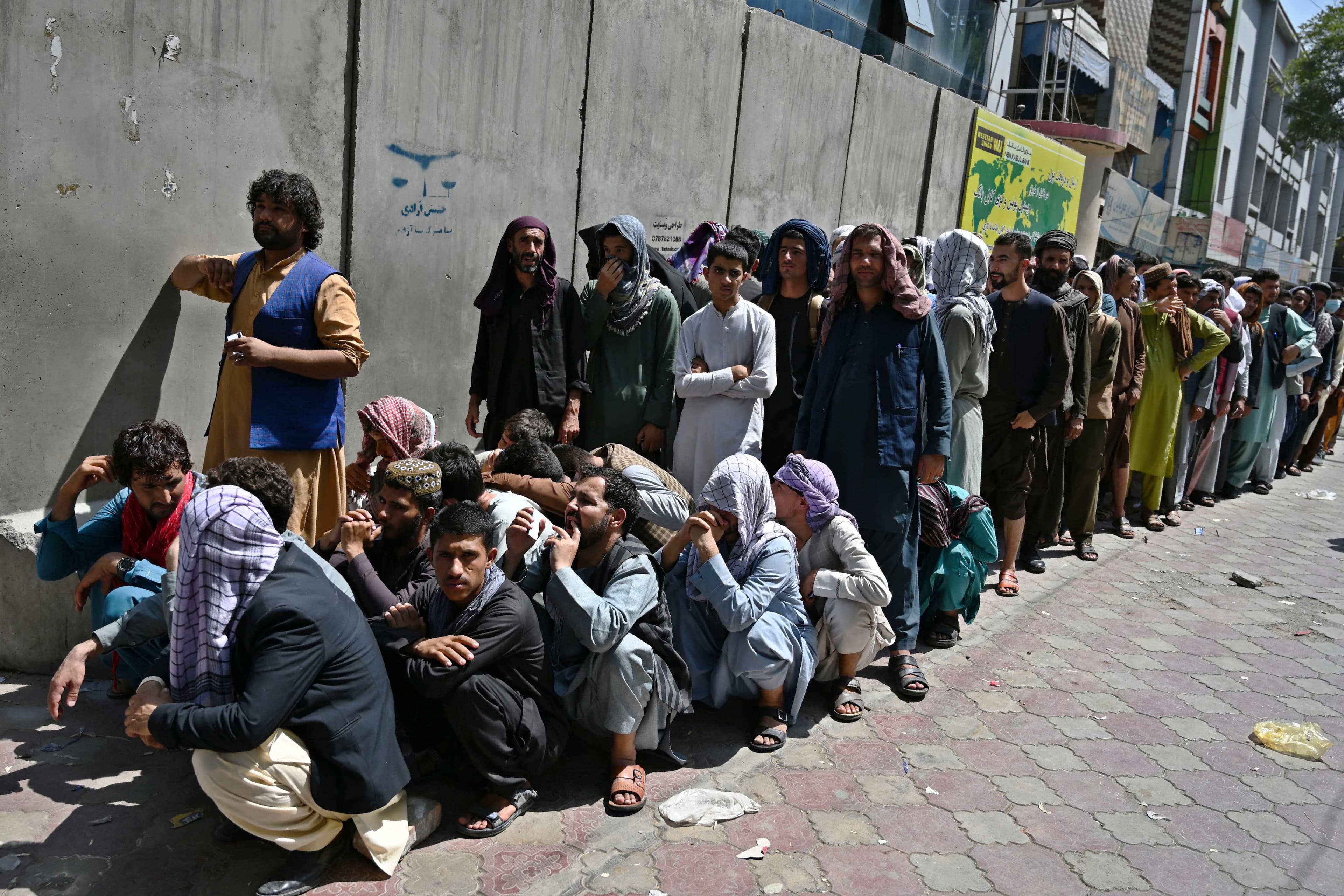 Des Afghans font la file devant une banque de Kaboul pour y retirer de l'argent.