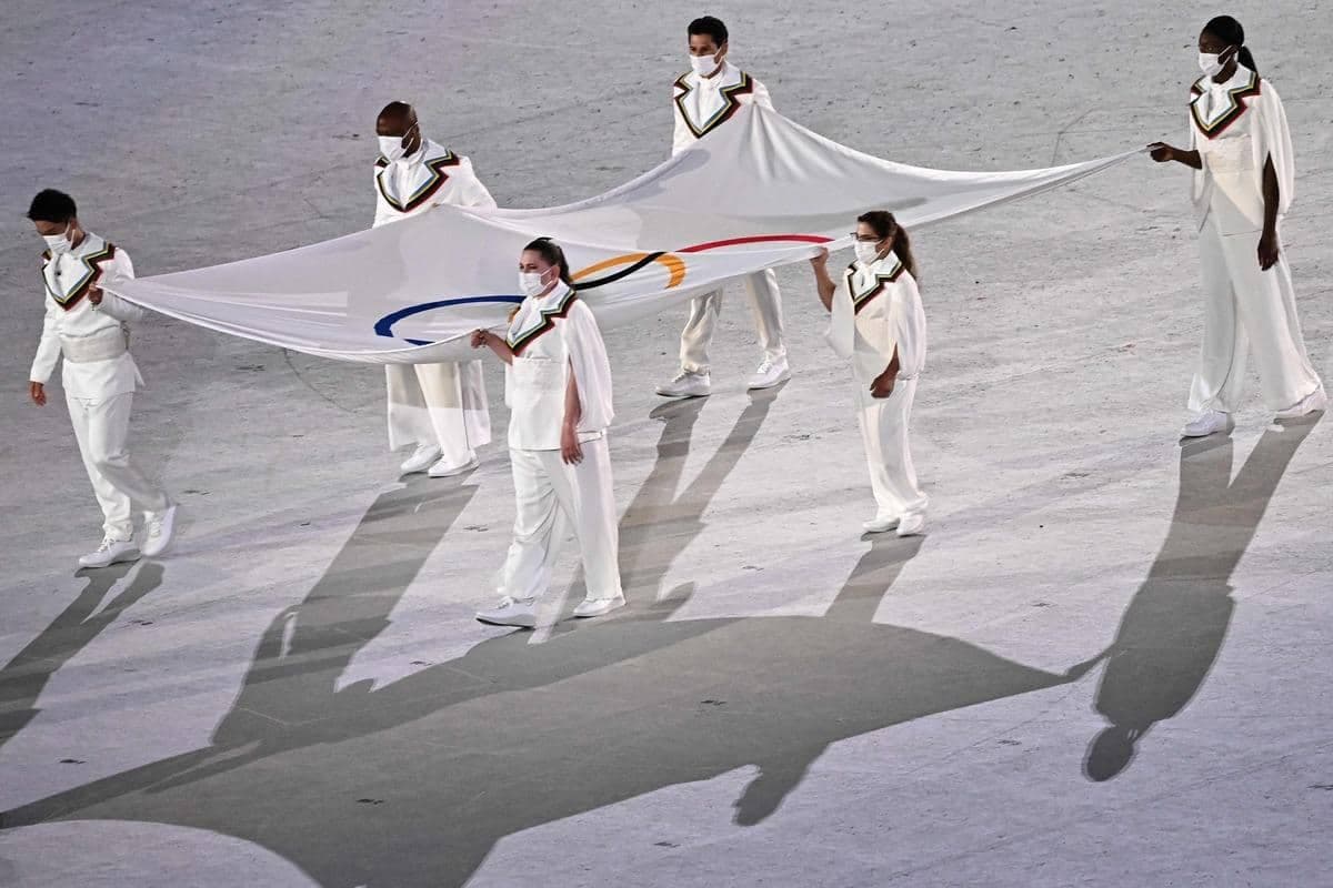 Des personnes s'étant impliquées dans le combat contre la COVID-19 ont porté le drapeau olympique.