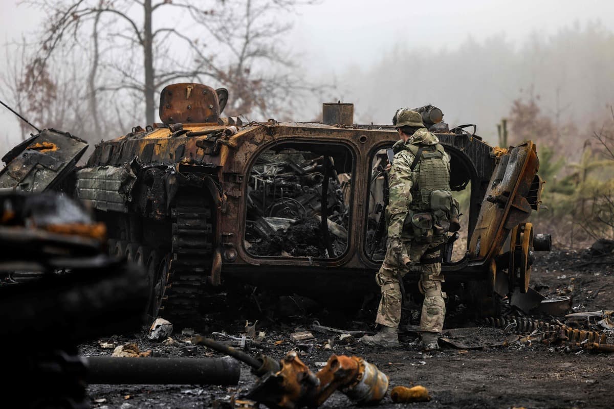 Un soldat ukrainien près d’un tank russe qui a brûlé.