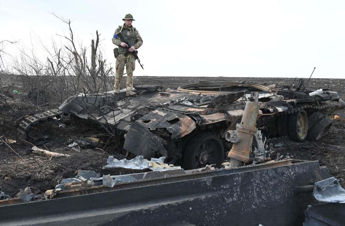 Un soldat ukrainien sur un tank russe qui a brûlé.