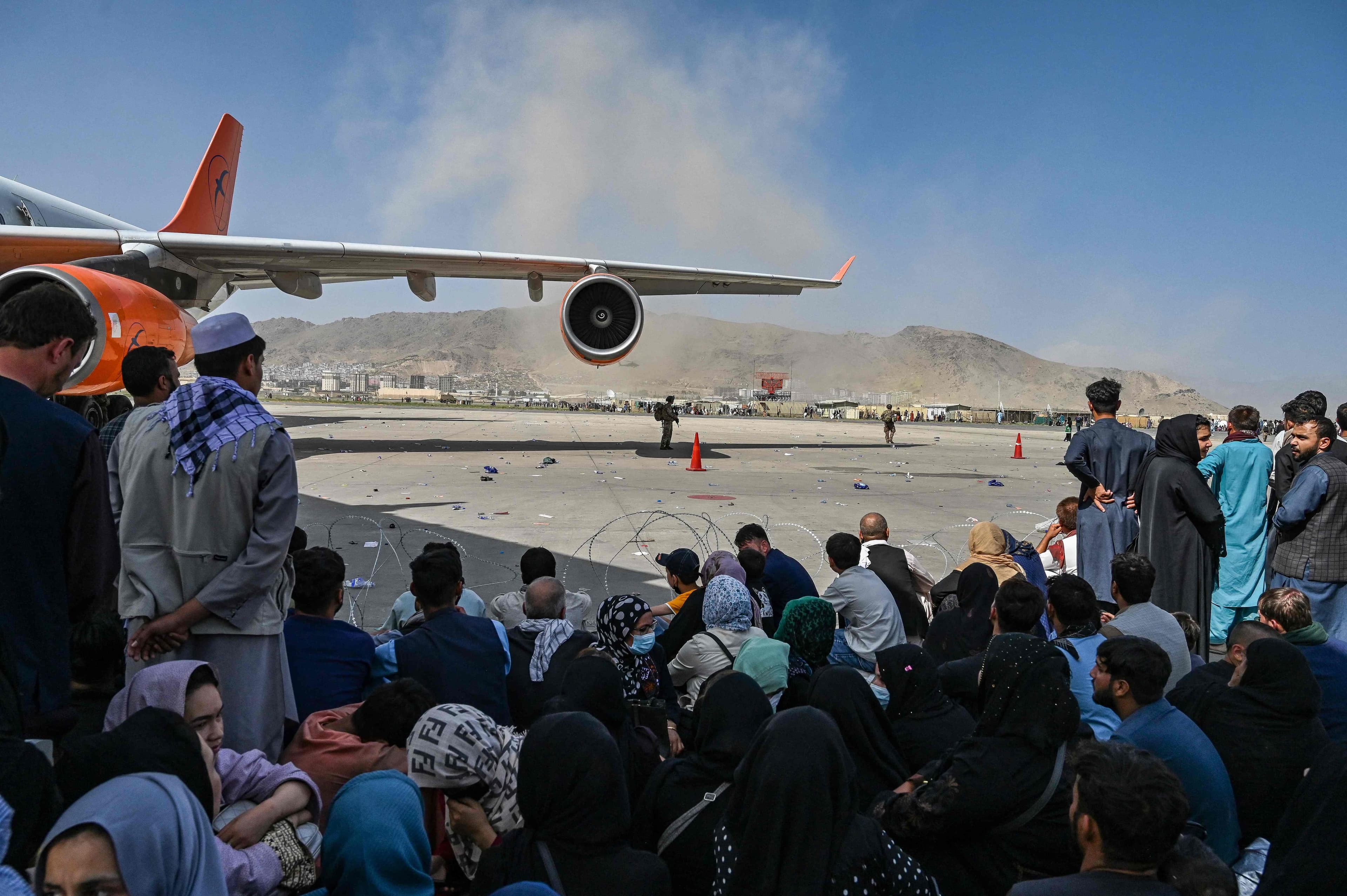 Des Afghans assis sur le tarmac de l'aéroport de Kaboul.