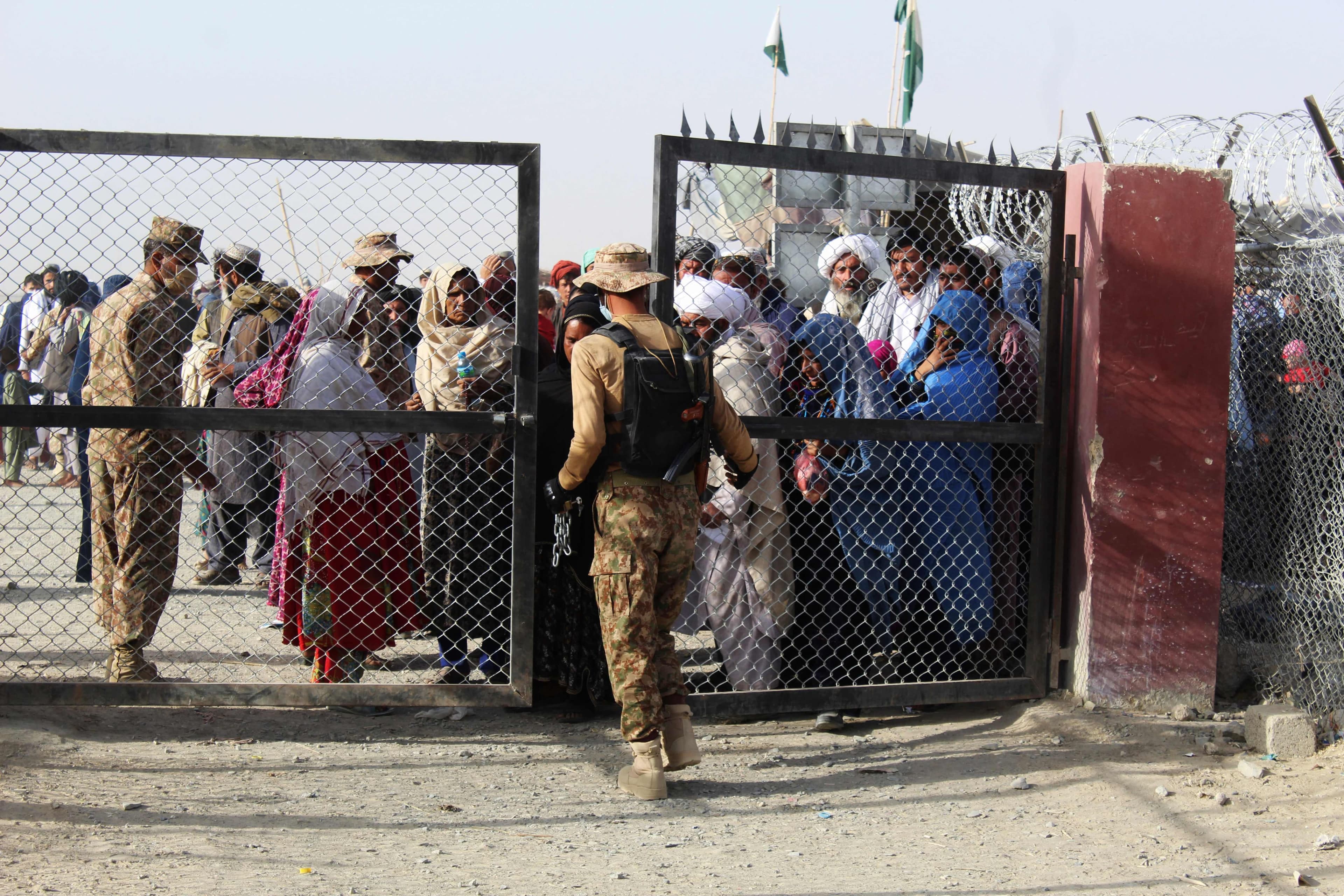Un soldat pakistanais garde les portes de la frontière entre l'Afghanistan et le Pakistan, alors que des citoyens afghans sont en attente de traverser.