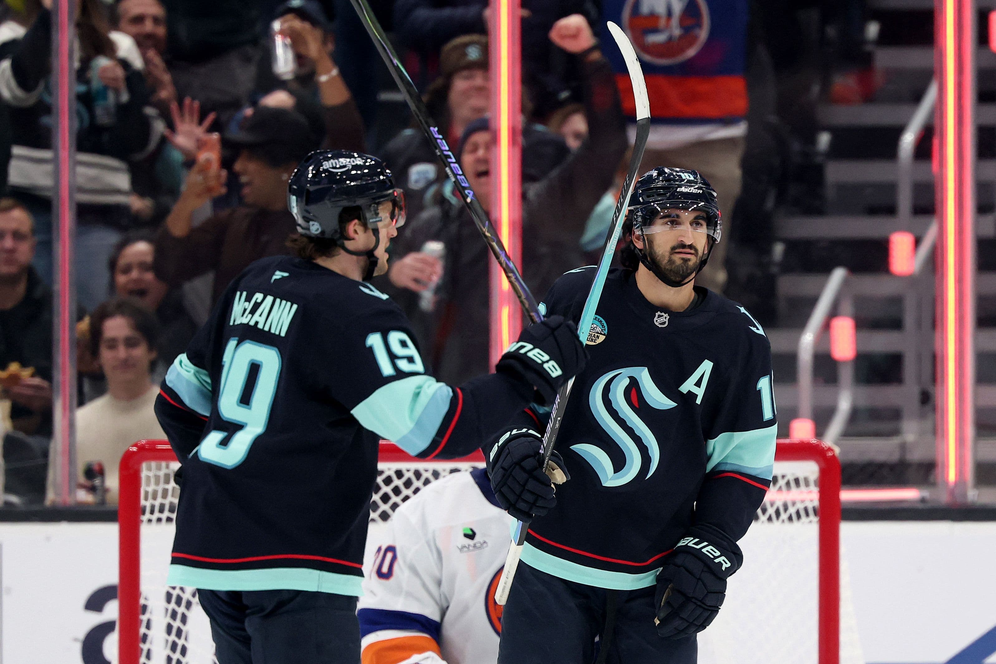 Matty Beniers, félicité par Jared McCann, après avoir marqué un but contre les Islanders, le 21 janvier 2026, devant la foule du Climate Pledge Arena.