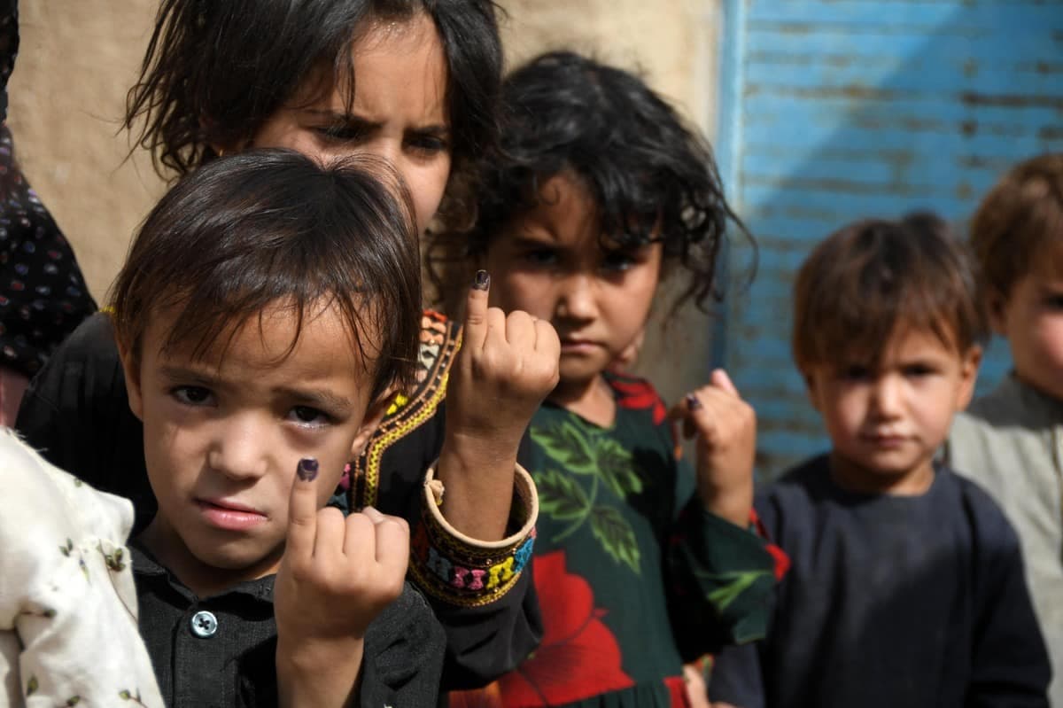 De jeunes Afghans montrant leur petit doigt marqué de noir, après avoir reçu leur vaccin contre la polio.