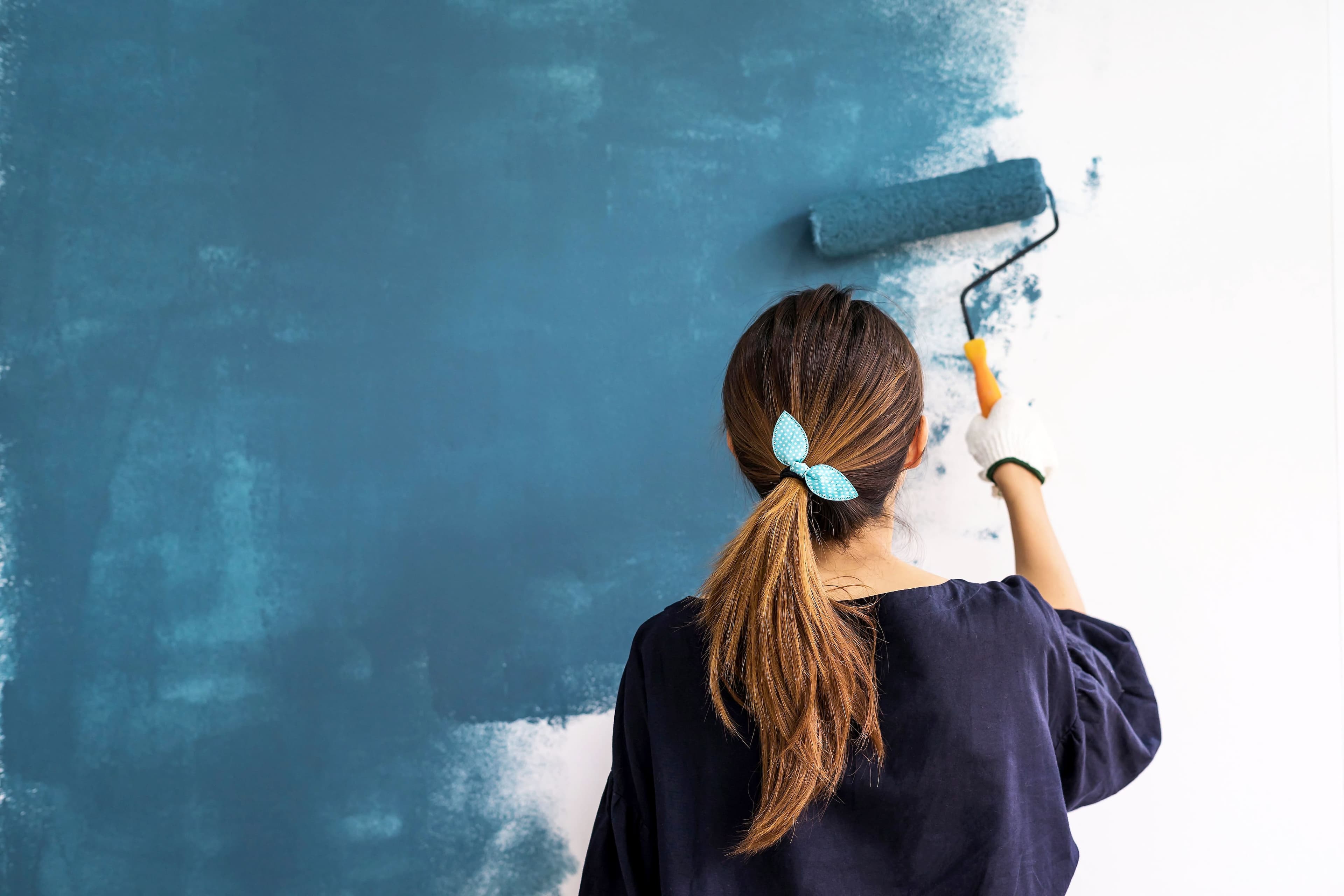 Une femme peint un mur intérieur