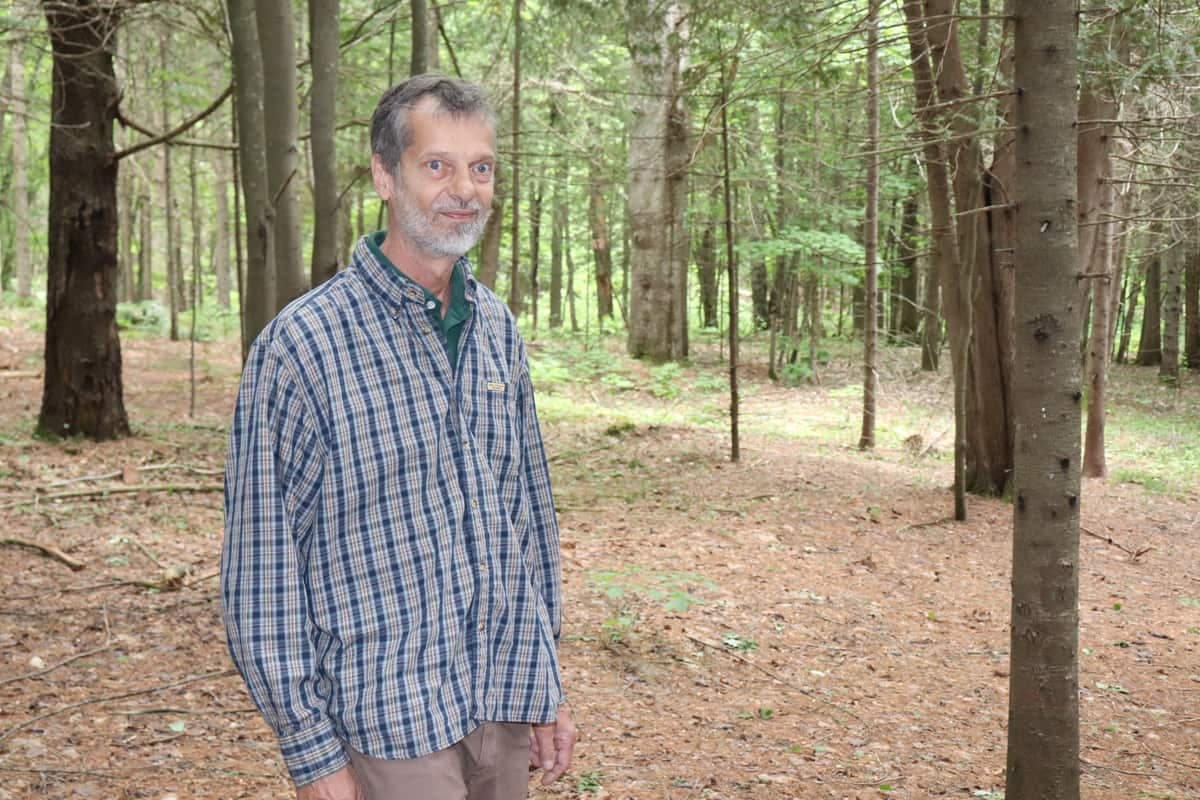 L’historien amateur Guillaume Petit pose à l’endroit où a été construite la première église, dans le 5e Rang, tout juste à côté du presbytère et du cimetière. Une forêt touffue recouvre aujourd’hui le site.