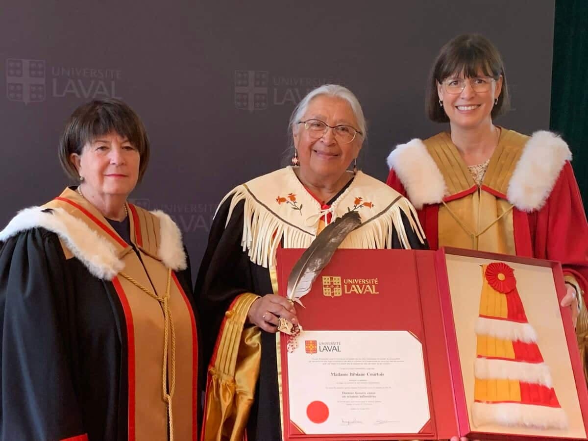 L'infirmière autochtone Bibiane Courtois, en compagne de la secrétaire générale Monique Richer (à gauche) et de la rectrice Sophie D'Amours (à droite), a reçu un doctorat honorifique de l'Université Laval pour sa carrière remarquable et son engagement à défendre les droits des femmes et la culture des Premières Nations.