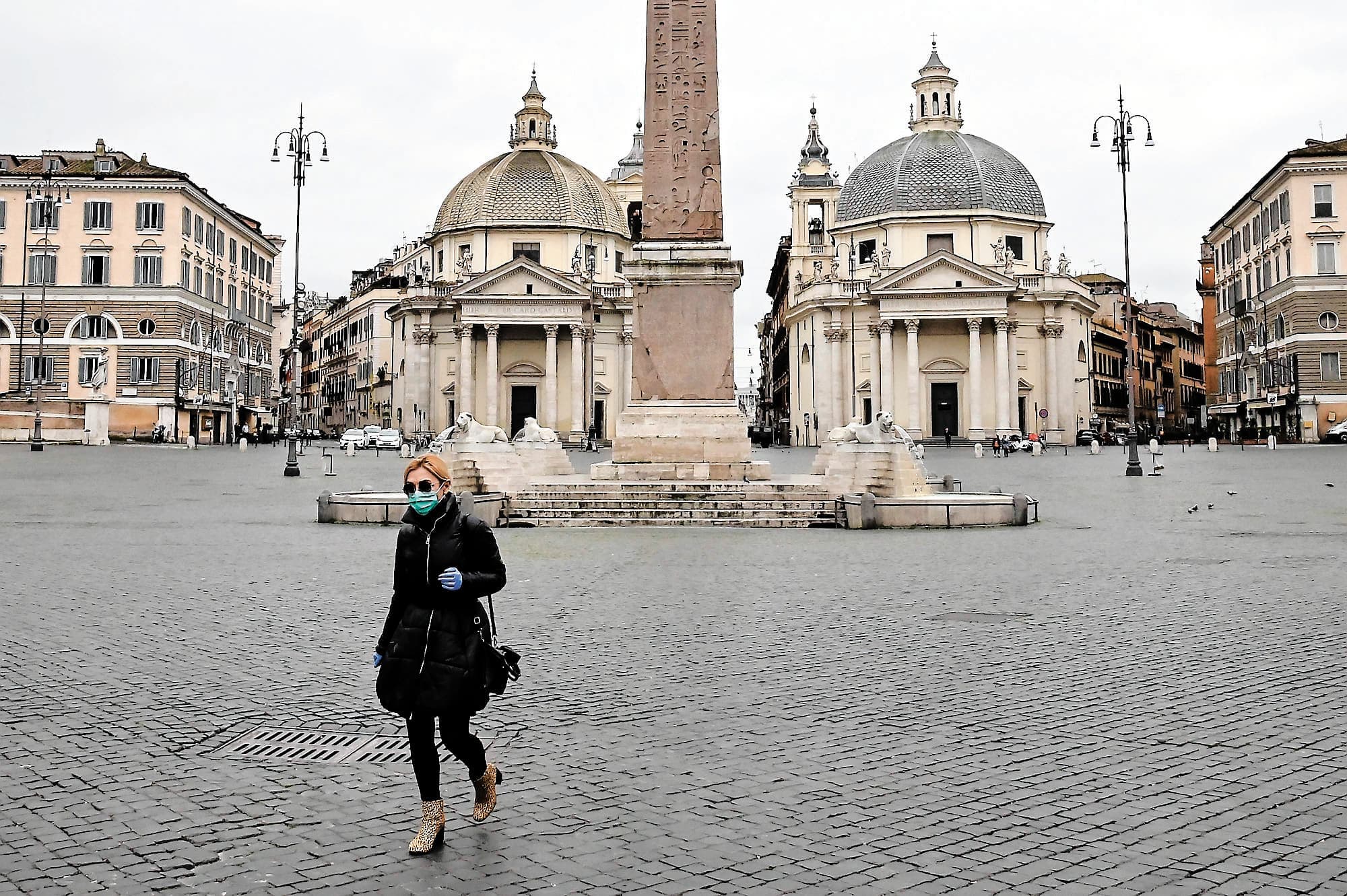 En Italie, la population a été durement touchée. Sur la photo, on voit une femme portant un masque qui déambule sur la piazza del Popolo déserte, à Rome, vendredi.