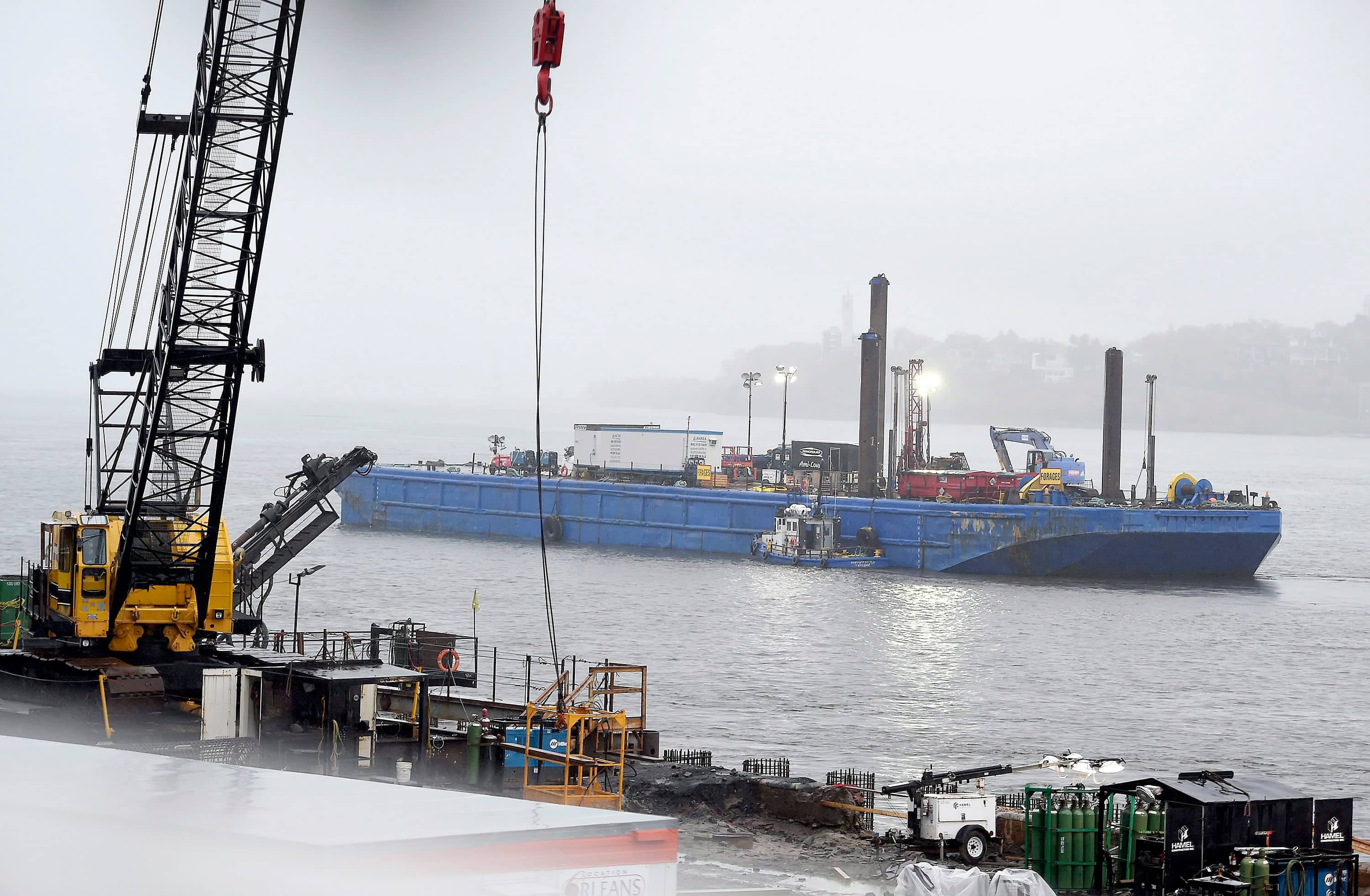 La barge de forage est amarrée dans le fleuve, près de la gare fluviale de Québec et des bâtiments de la Garde côtière canadienne.
