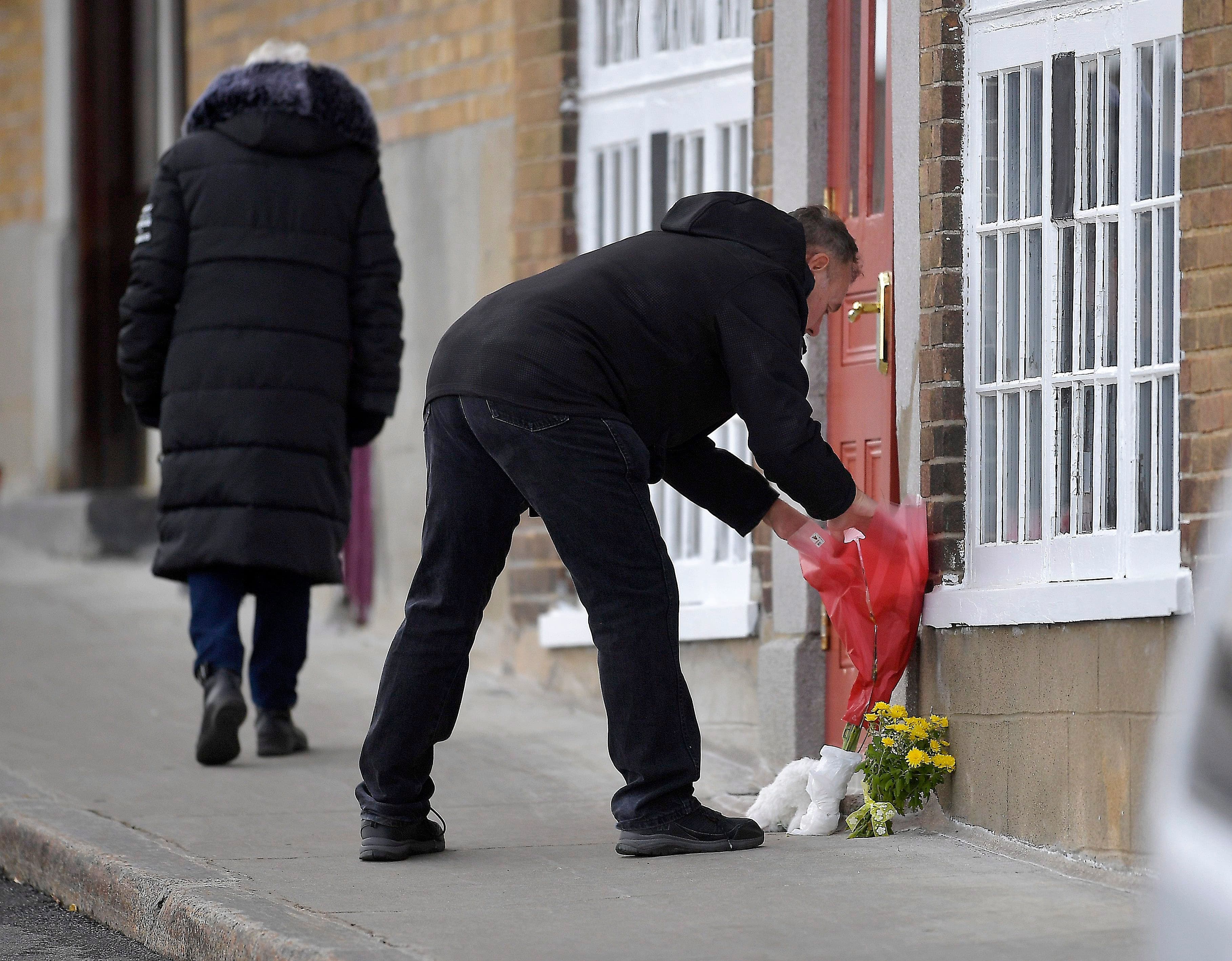 Un homme déposant des fleurs devant le logement.