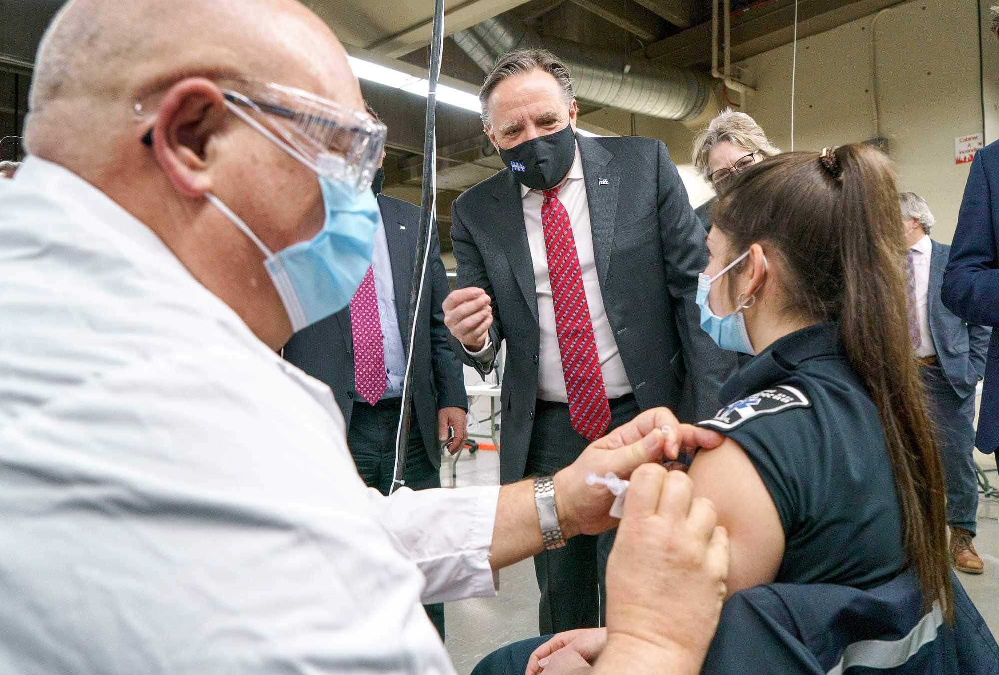 Le premier ministre du Québec, François Legault, regardait une femme se faire vacciner contre la COVID-19, mardi, au Stade olympique de Montréal, qui deviendra le plus important centre de vaccination de la province.