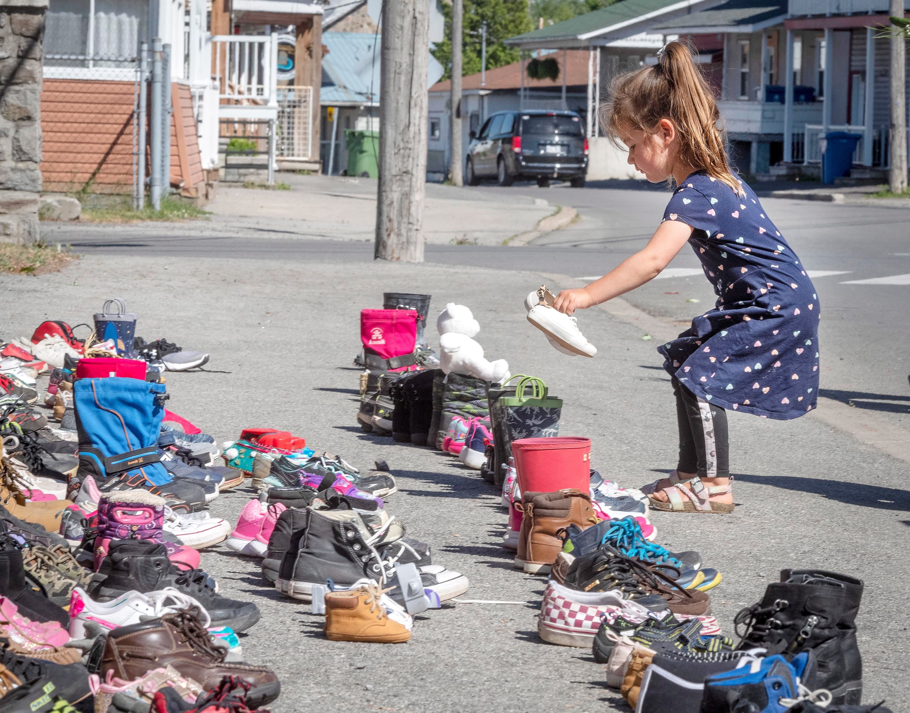 Une fillette de 4 ans dépose une paire de ses chaussures devant l’église Saint-Francois-Xavier à Kahnawake, près de Montréal, en mémoire des 215 enfants retrouvés morts dans une fosse commune d’un pensionnat autochtone en Colombie-Britannique.
