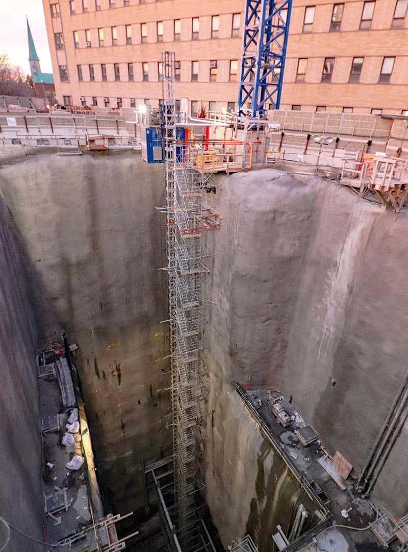 Le chantier de la station Édouard-Montpetit du futur REM, à Montréal, actuellement en construction, impressionne par son gigantisme. Quatre ascenseurs à haute capacité et haute vitesse doivent permettre aux futurs usagers de descendre dans le puits vertical. De courts escaliers mécaniques les guideront ensuite vers les quais.