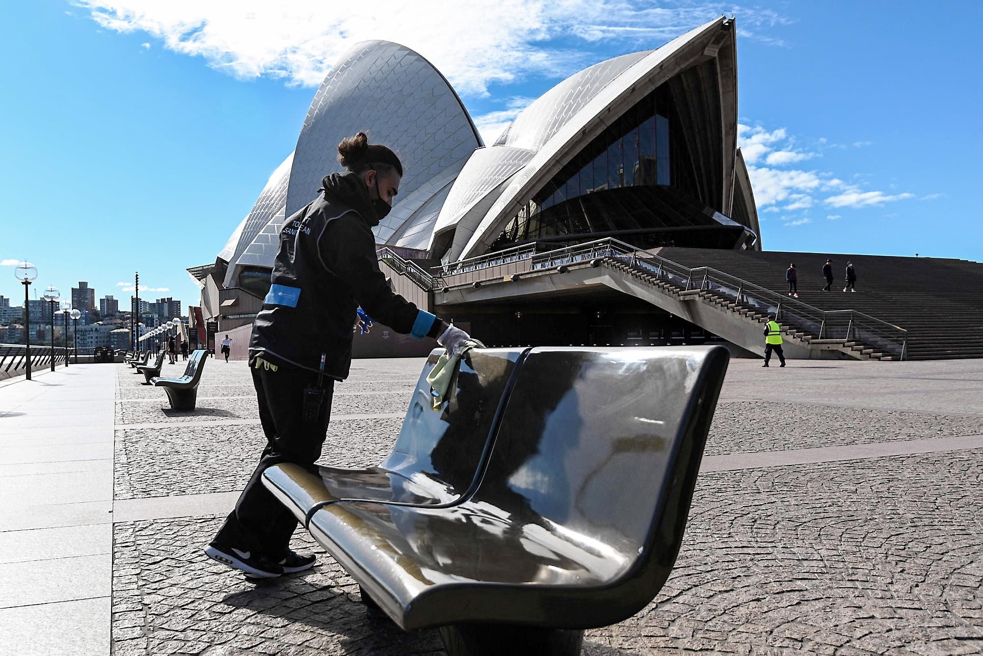 Un travailleur nettoie les bancs publics près de l’Opéra de Sydney dont les abords étaient déserts, samedi, après que les autorités ont verrouillé des zones centrales de la plus grande ville d’Australie.
