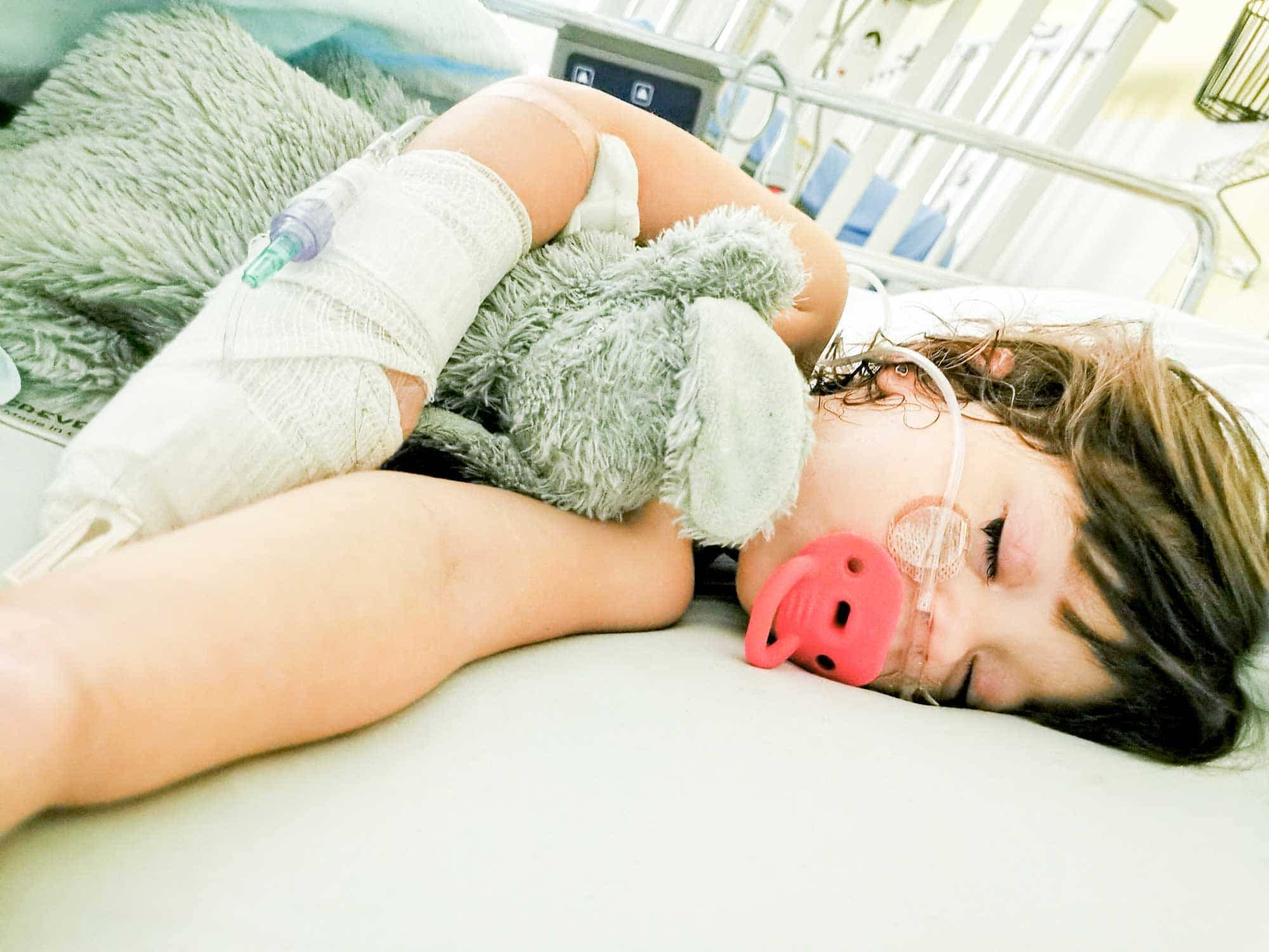Amy sur son lit d’hôpital avec le soluté branché dans la main qui a engendré ses doigts tout noirs en raison d’un problème.