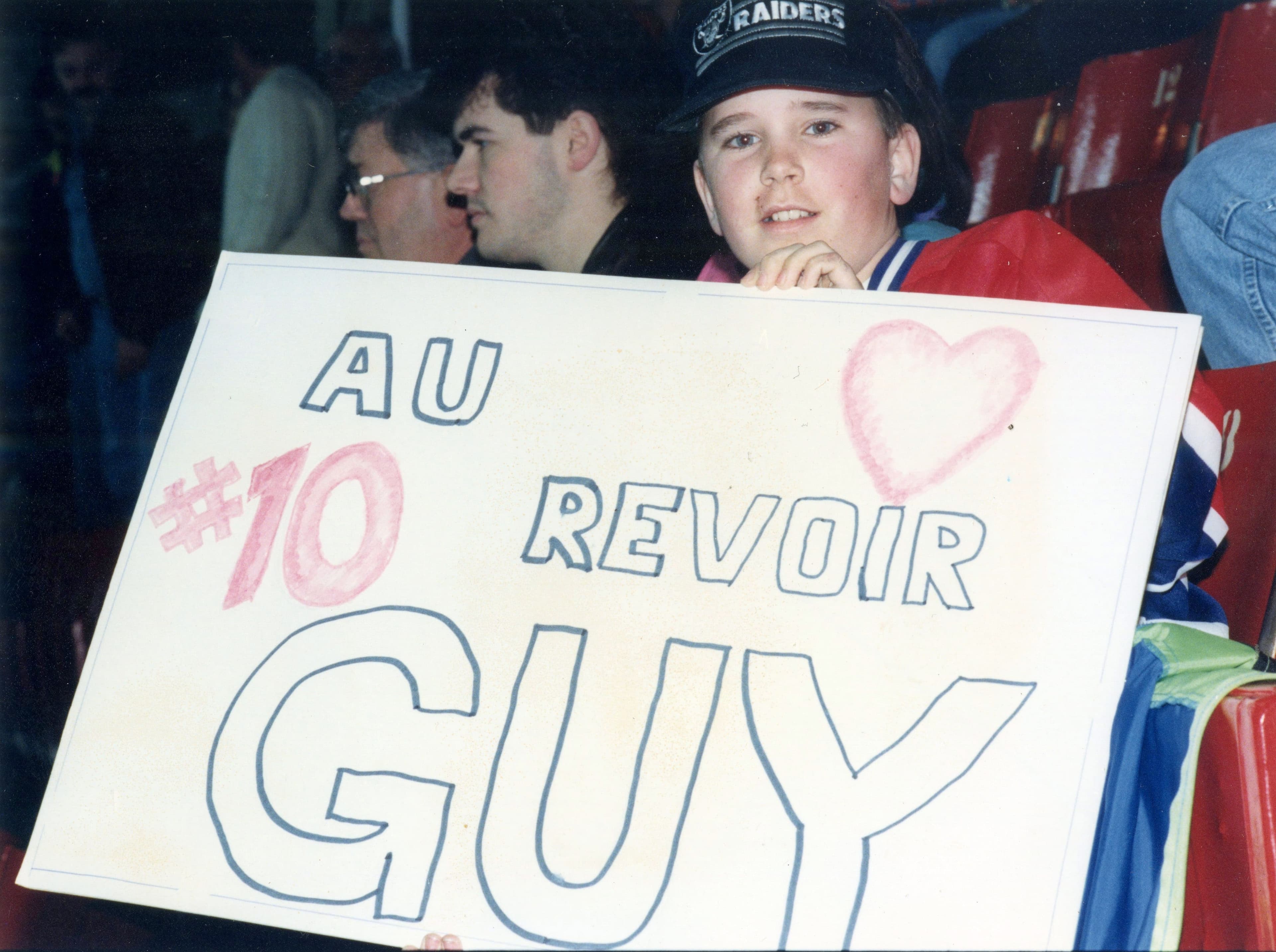 Un jeune amateur exhibe une pancarte sur laquelle il dit au revoir au héros du jour.