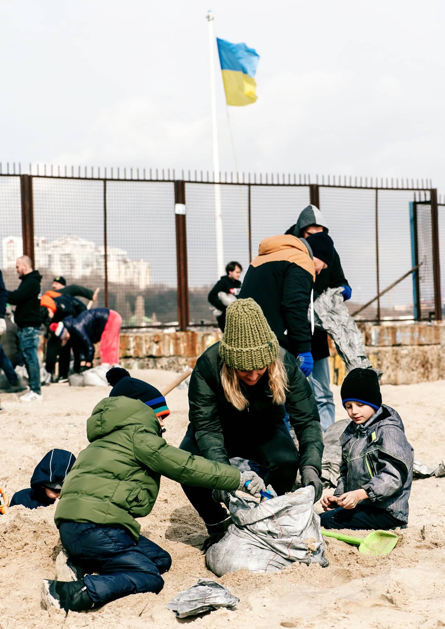 Avec des dizaines de citoyens, une femme et des enfants remplissent des sacs de sable, à Odessa, pour protéger leur ville de l'imminente attaque russe.