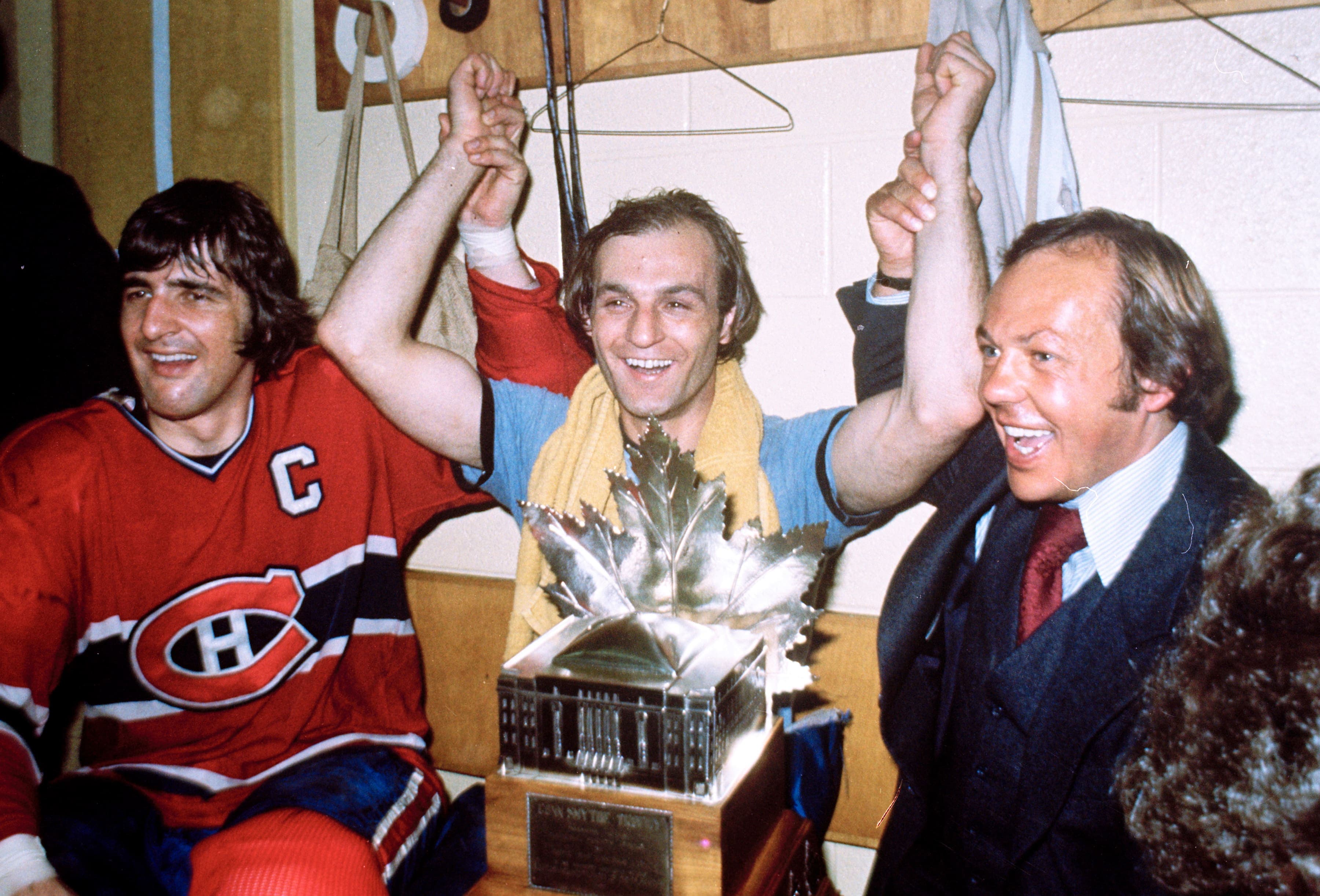 Entouré par son capitaine Serge Savard et par Yvan Cournoyer, le Démon blond a le sourire du vainqueur avec le trophée Conn Smythe sur ses genoux.