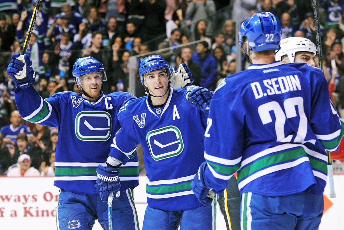 Alex Burrows (centre) célèbre avec les frères Henrik (gauche) et Daniel (droite) Sedin après un but contre les Flames de Calgary, le 6 avril 2013.