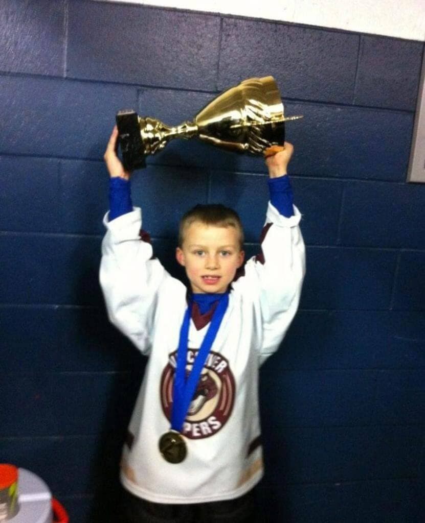 Connor Bedard soulevant l'un de ses nombreux trophées de champion.