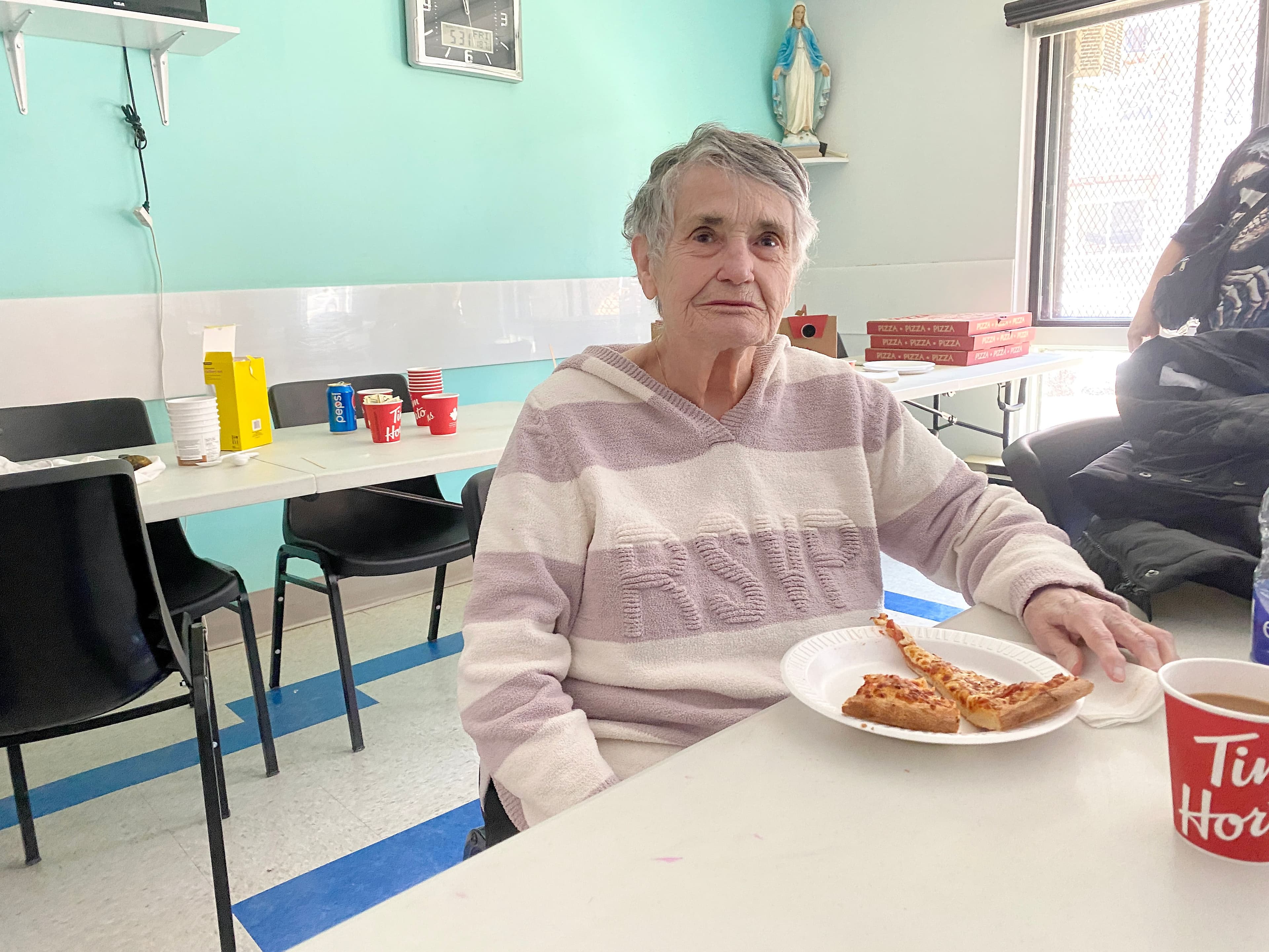 Monique Bélisle, présidente du comité des résidents du HLM, en train de manger de la pizza apportée par des citoyens venant en aide au HLM.