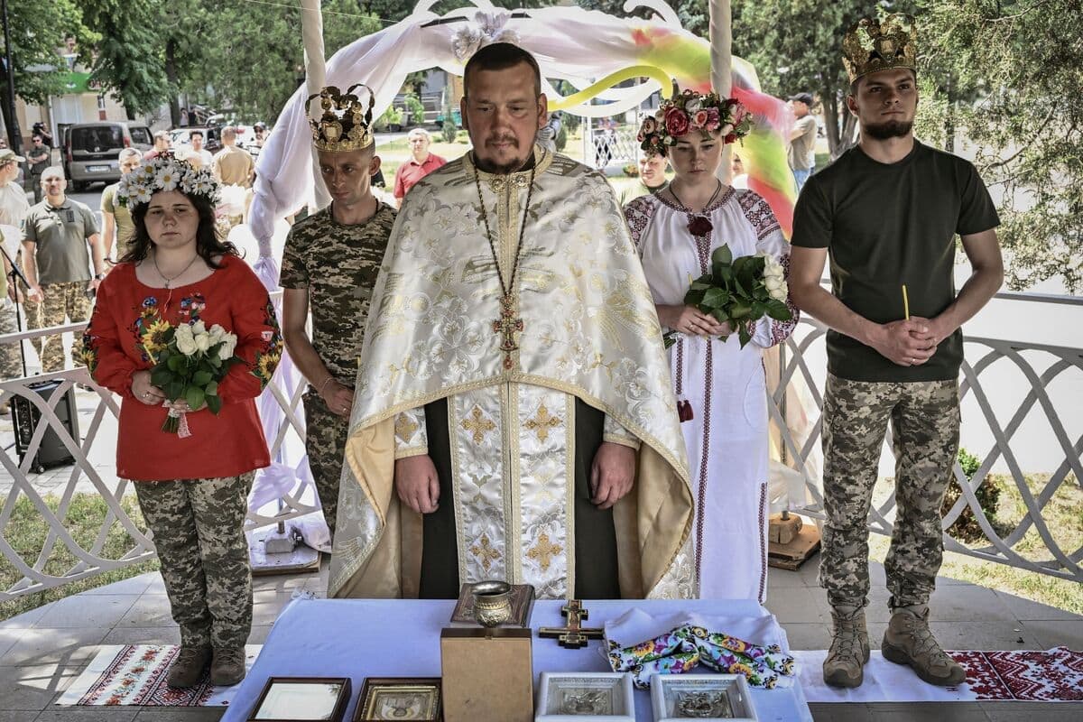 Les soldats ukrainiens Kristina (2e à partir de la droite) et Vitalii Orlich, tous deux âgés de 23 ans, ainsi que Khrystyna Lyuta (à gauche), 23 ans, et Volodymyr Mykhalchuk, 28 ans, se sont mariés à Droujkivka, dans la région du Donbass, le 12 juin 2022. (Photo de ARIS MESSINIS / AFP)