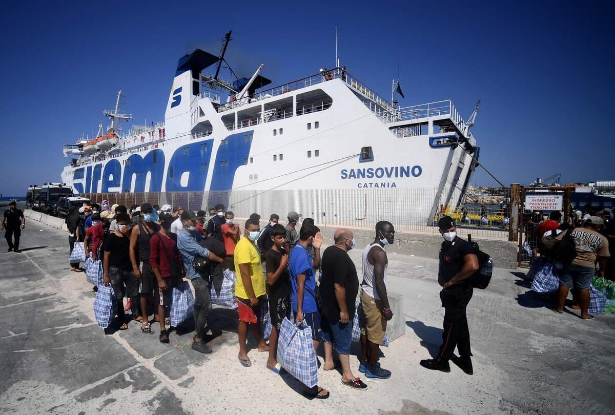 Des migrants attendent de pouvoir monter à bord d'un traversier, dans le sud de l'Italie.