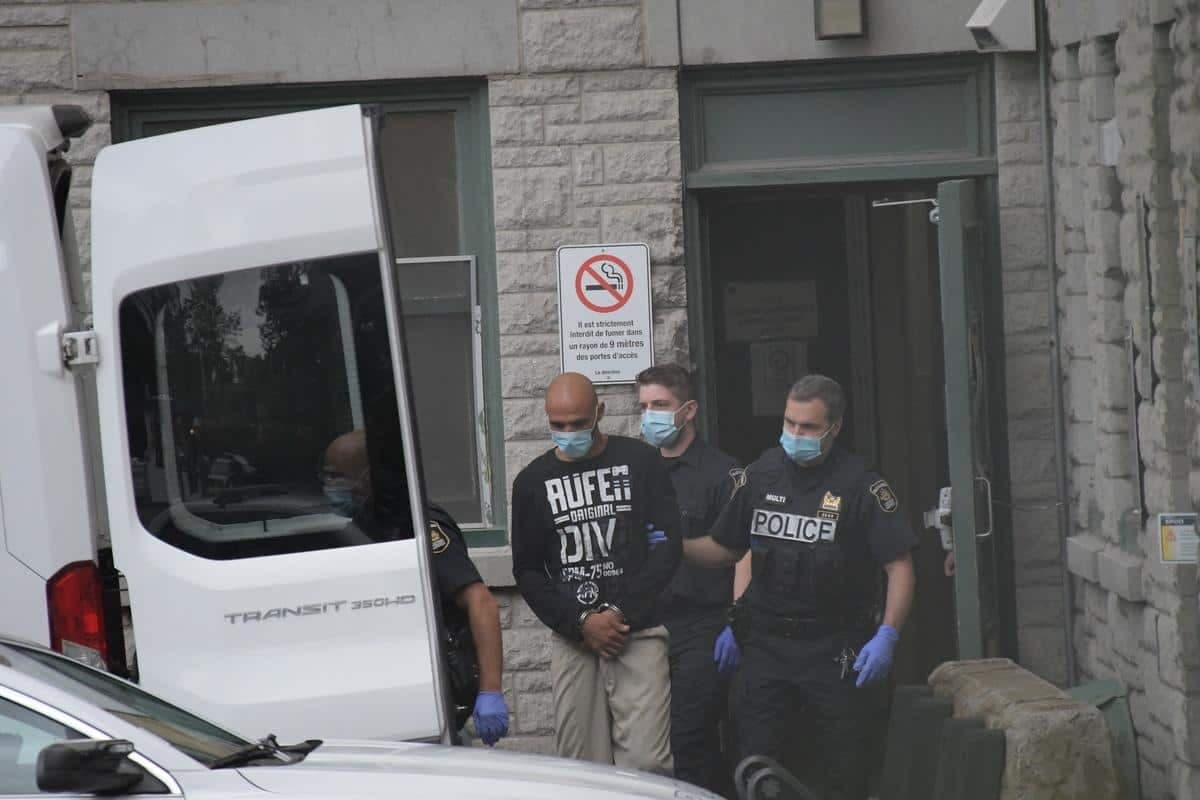 Menottes aux poignets, Noureddine Mimouni est escorté par des agents à sa sortie de la centrale de police du parc Victoria, mardi après-midi.