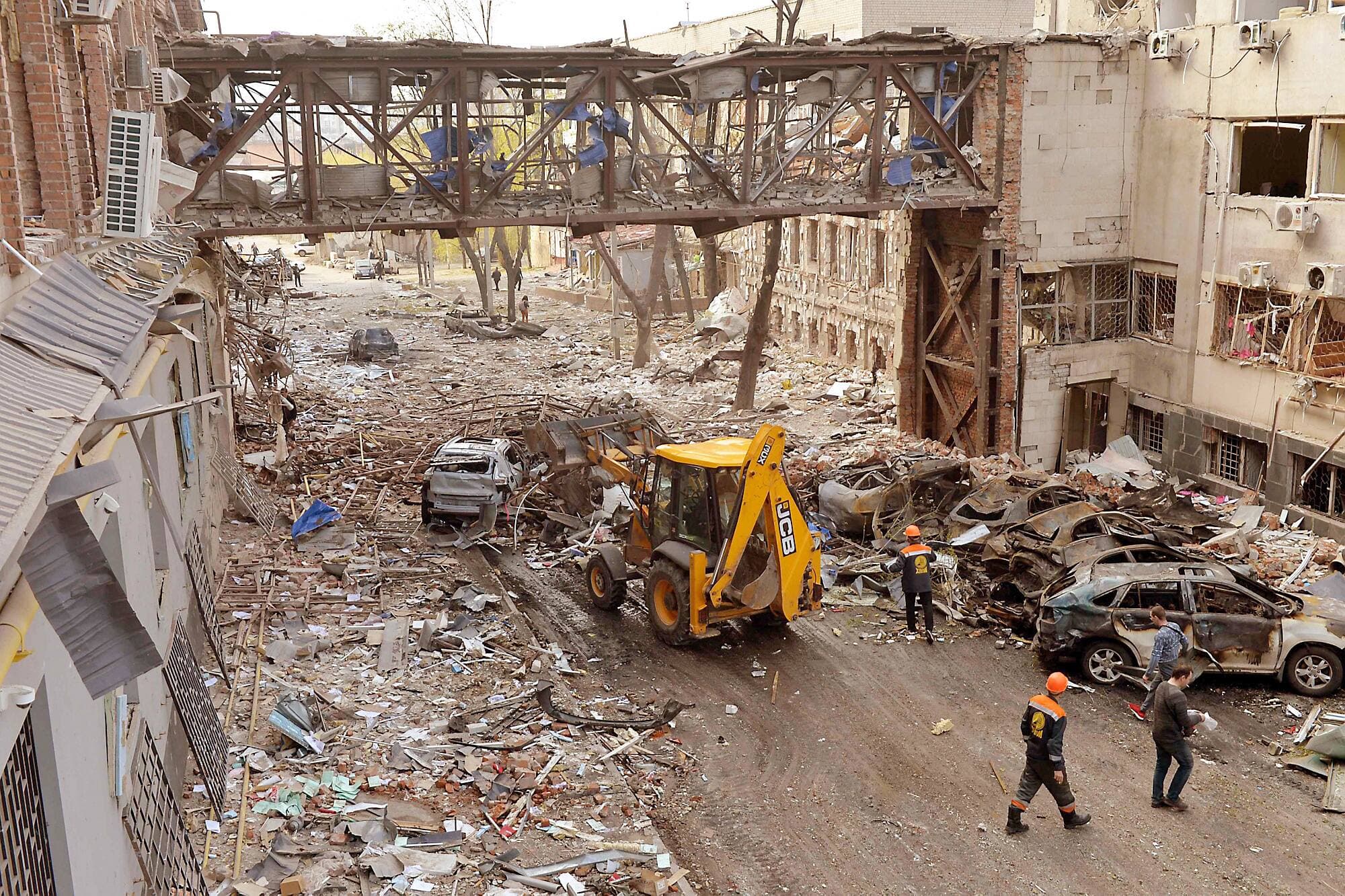Des travailleurs nettoient des bâtiments détruits suite à un bombardement qui a tué deux personnes, à Kharkiv.