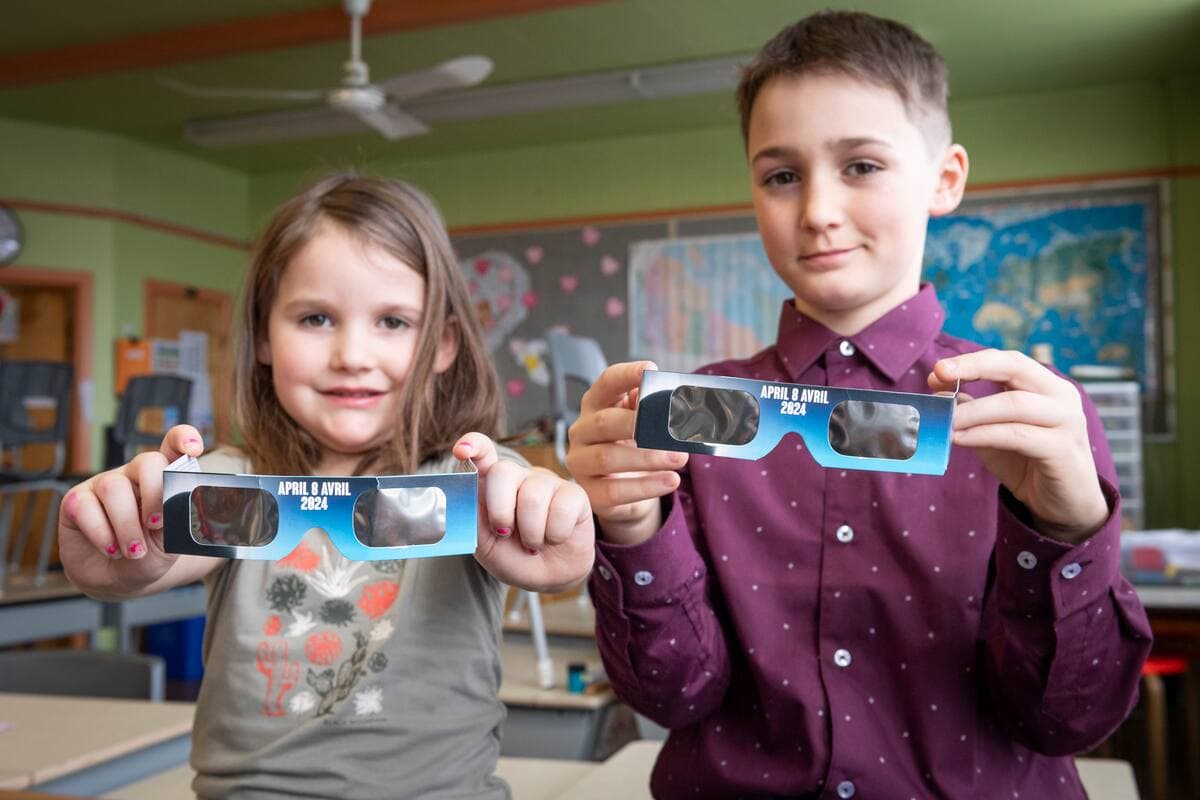 Les enfants de Camille Turcotte, directrice générale de l'Association pour l'enseignement de la science et de la technologie au Québec, Géraldine Grisé, 5 ans, et Léopold Grisé, 10 ans, prennent la pose dans une classe avec des lunettes qui leur permettront d'admire l’éclipse solaire du 8 avril.