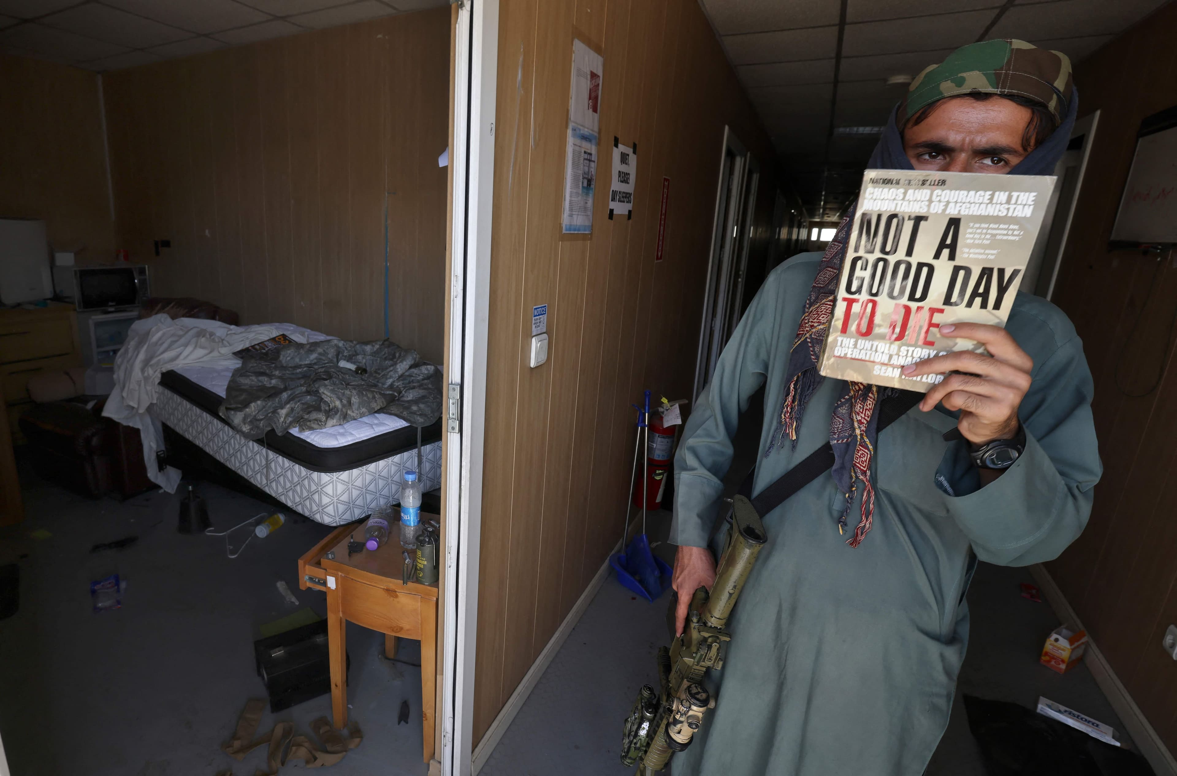 Un taliban montre un livre trouvé dans un camp militaire américain à l'aéroport de Kaboul.