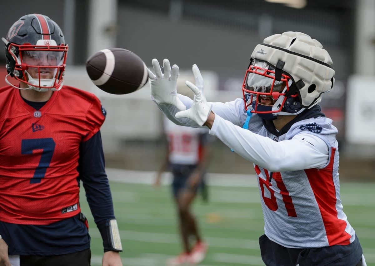 Austin Mack attrape un ballon sous le regard attentif du quart-arrière Cody Fajardo, lors de l'entraînement du mercredi 21 août 2024, au stade Hébert.
