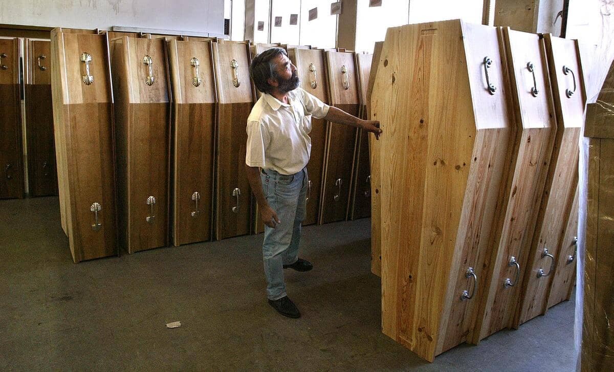Dans cette photo d'archives prise à Paris en août 2003, on voit un employé des pompes funèbres devant des cercueils qui s'entassent, alors que des milliers de personnes sont mortes lors d'une vague de chaleur.