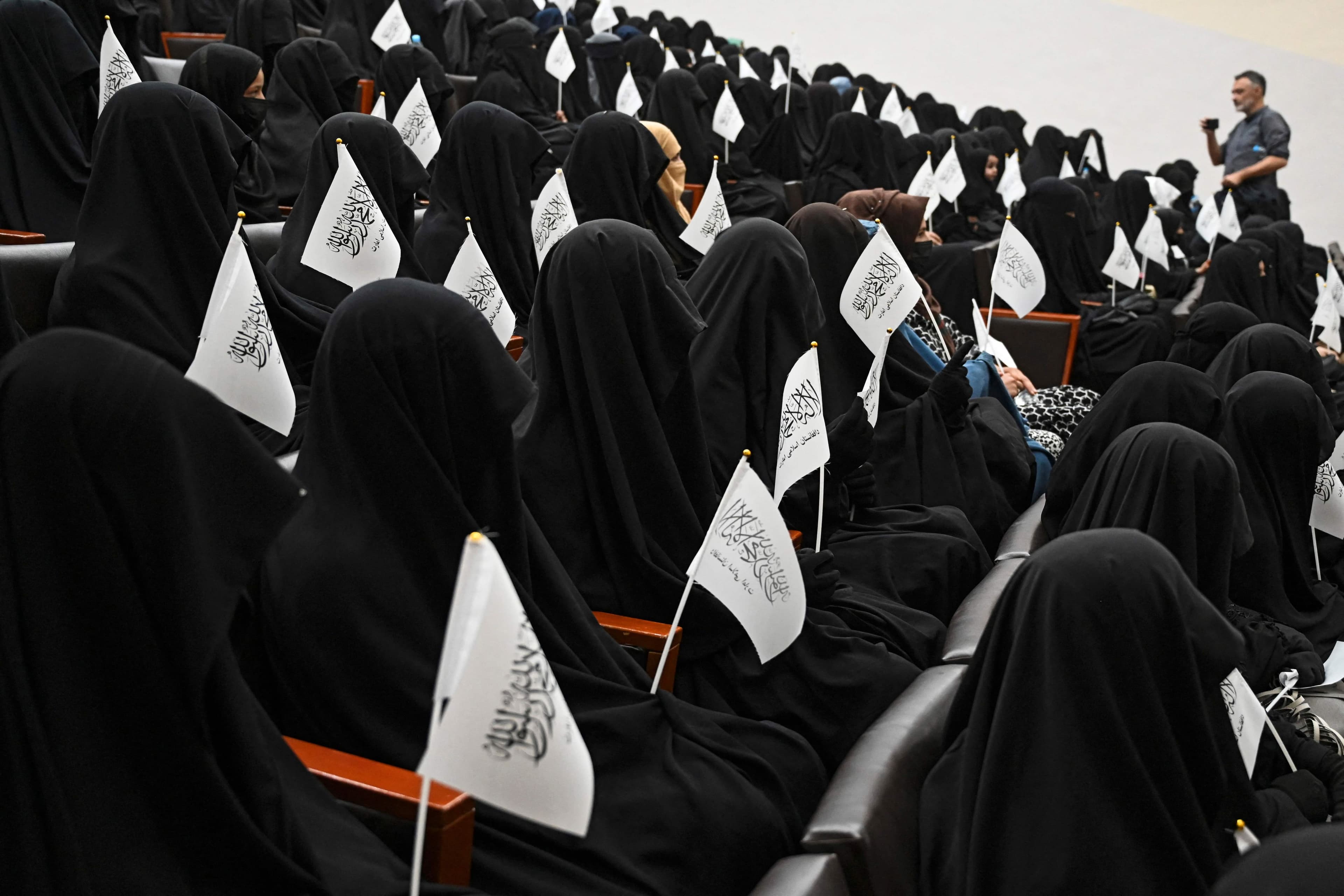 Des étudiantes voilées tiennent des drapeaux talibans lors d'un rassemblement pro-taliban à l'université Shaheed Rabbani, à Kaboul.
