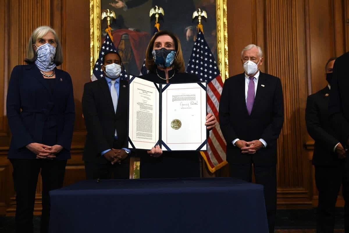 La présidente de la Chambre des représentants, Nancy Pelosi, tenant l’acte d’accusation de Donald Trump.