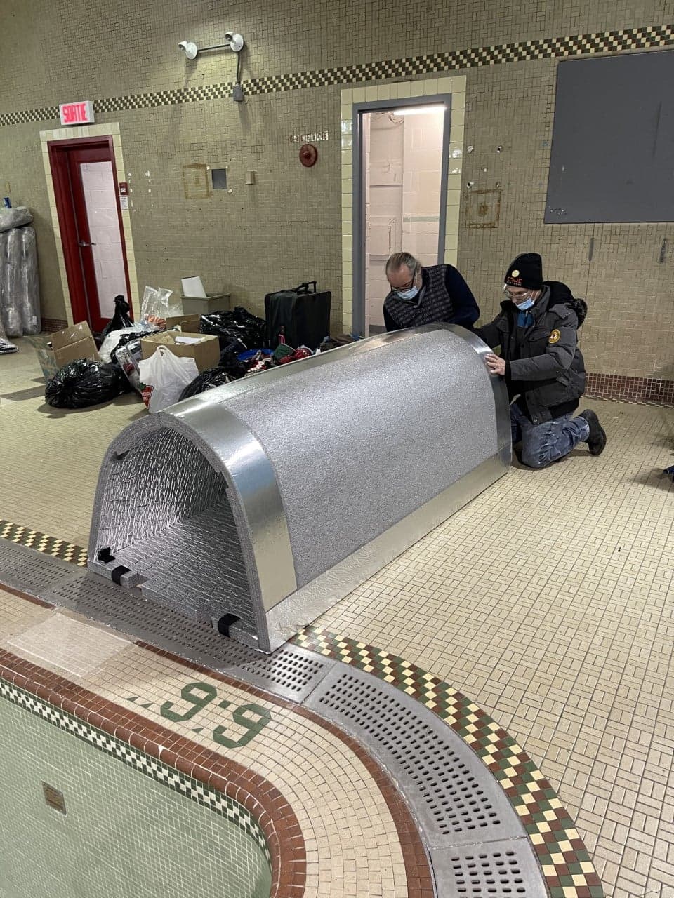 Sur le bord de la piscine désormais vide de l'ex-YMCA d'Hochelaga-Maisonneuve converti en refuge pour itinérants, le directeur de CARE Montréal Michel Monette et son adjoint Daniel Guillet assemblent leur premier Iglou.